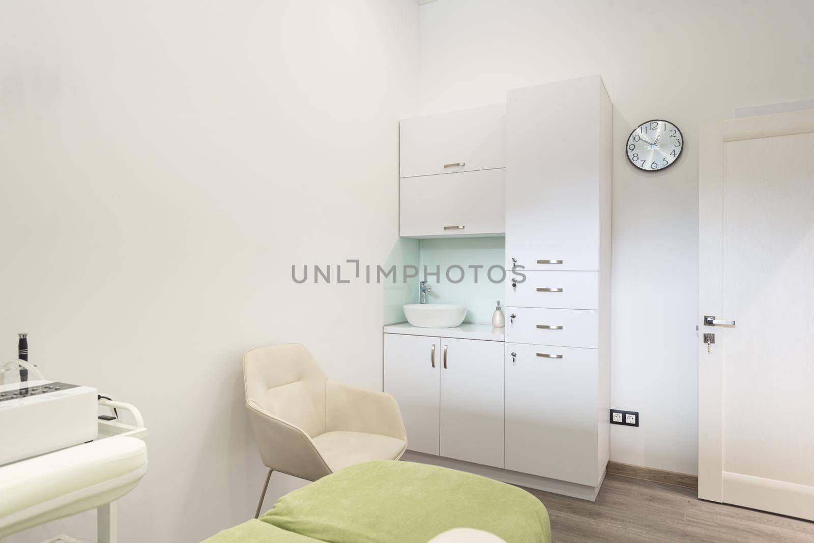 Beautiful interior of new salon, spa room, beauty parlour, or dermatological clinic with empty bed and modern skin care products on shelves and wall racks