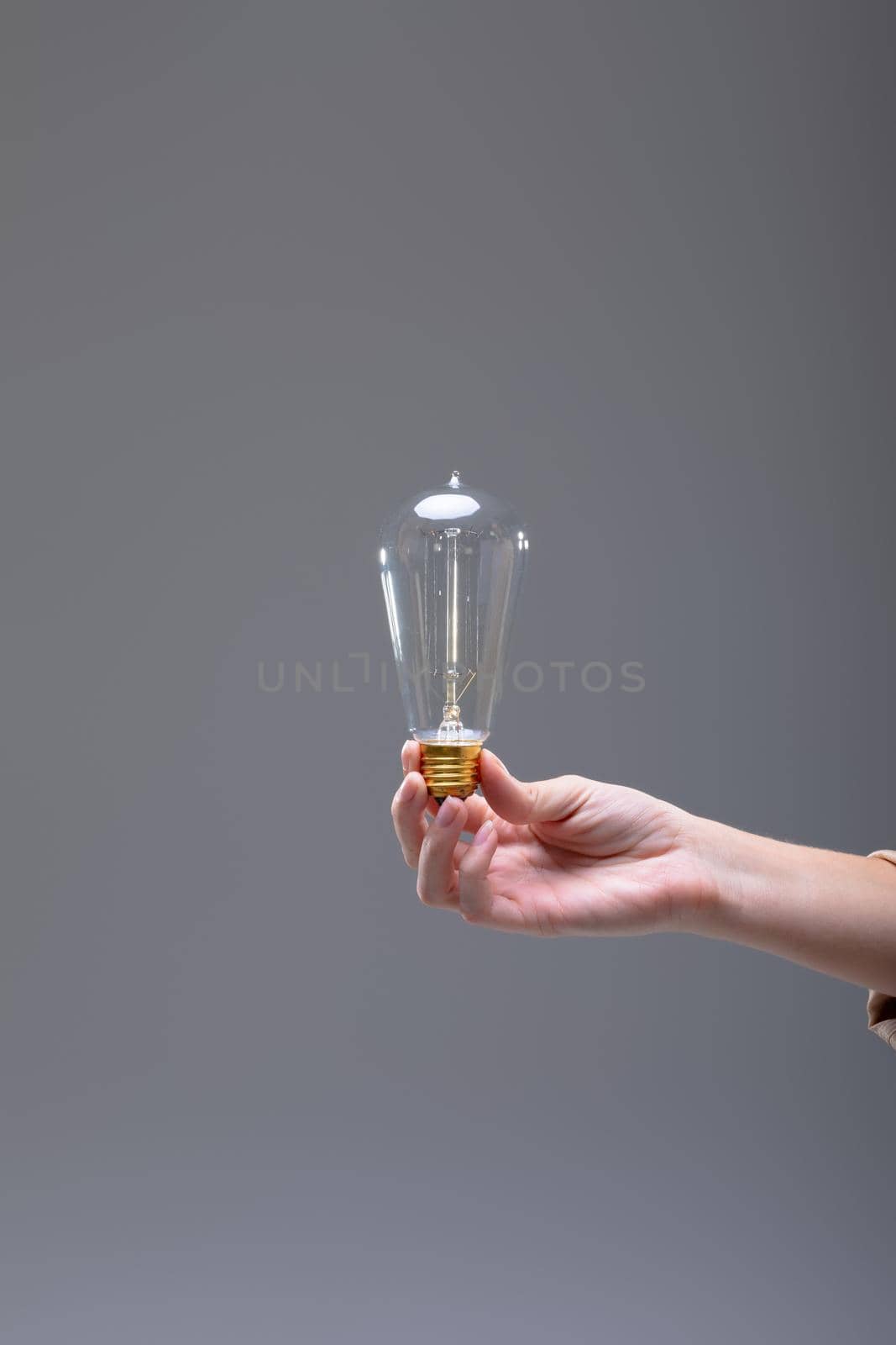 Close up of caucasian businesswoman holding light bulb, isolated on grey background by Wavebreakmedia