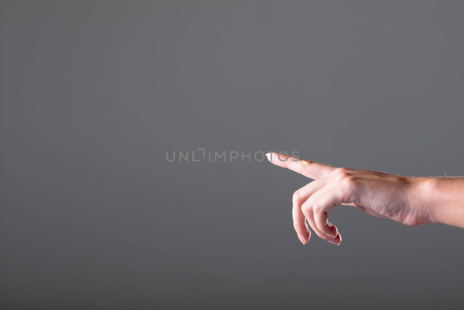 Close up of caucasian businesswoman pointing with her finger, isolated on grey background. business, technology, communication and growth concept.