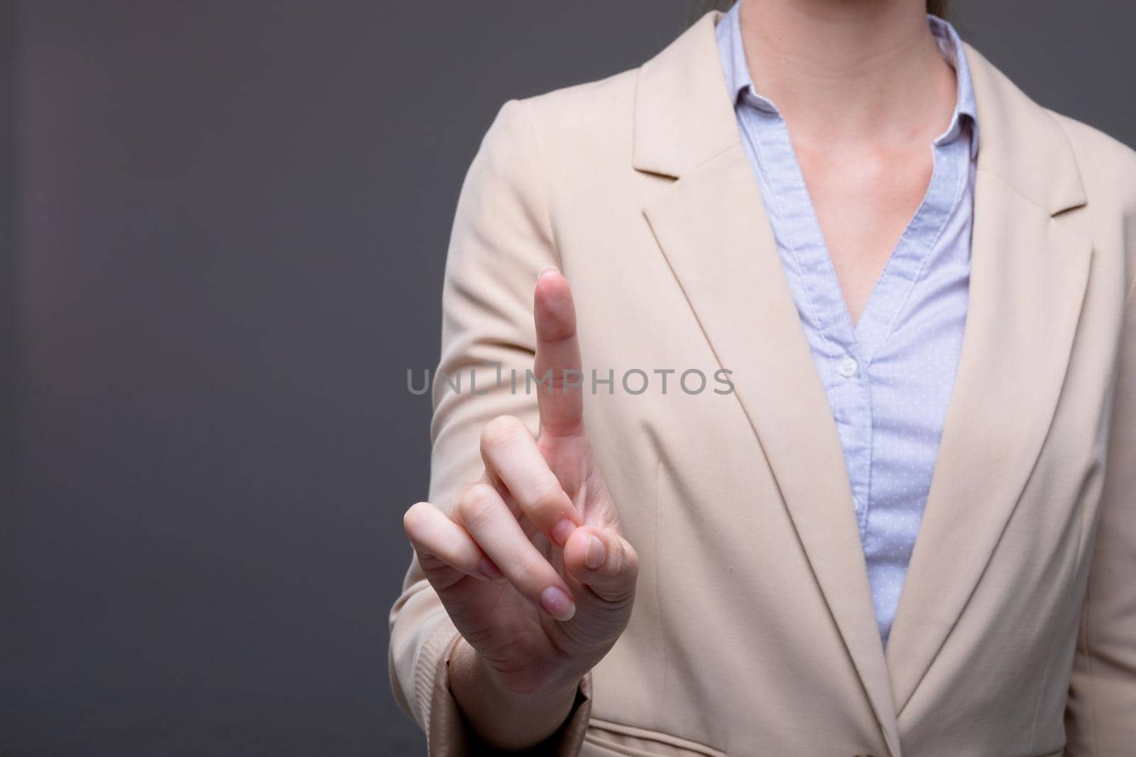 Midsection of caucasian businesswoman touching virtual interface on grey background. business, technology, communication and growth concept.