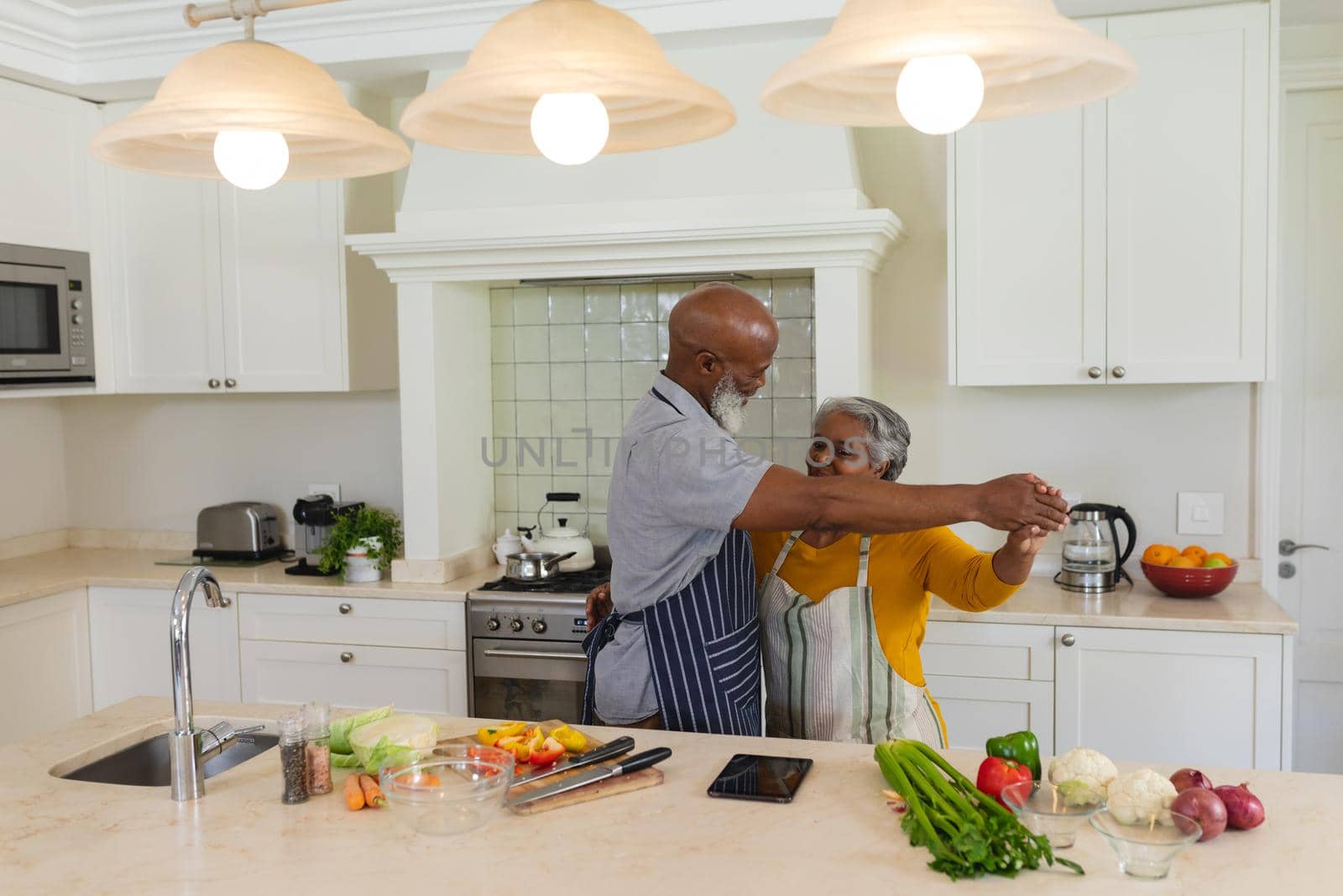 Senior african american couple dancing together in kitchen smiling. retreat, retirement and happy senior lifestyle concept.