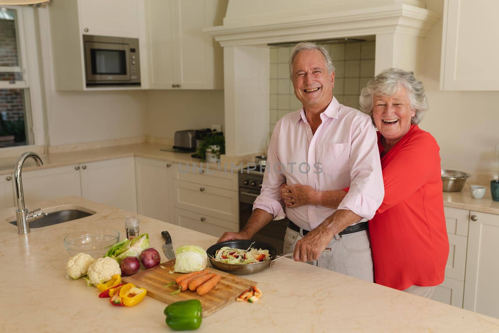 Portrait of senior caucasian couple cooking together and smiling in kitchen. retreat, retirement and happy senior lifestyle concept.