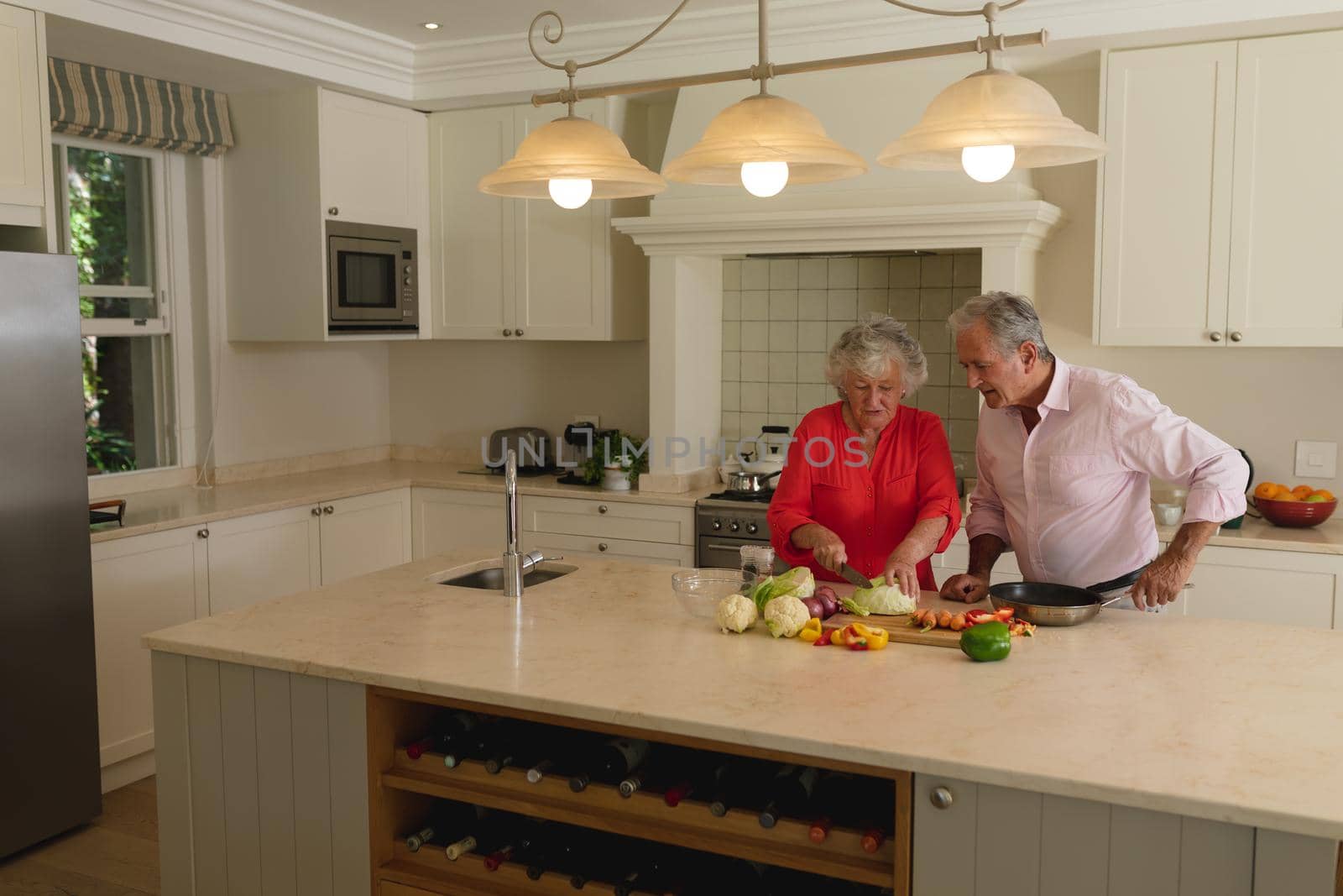 Senior caucasian couple cooking together and talking in kitchen. retreat, retirement and happy senior lifestyle concept.