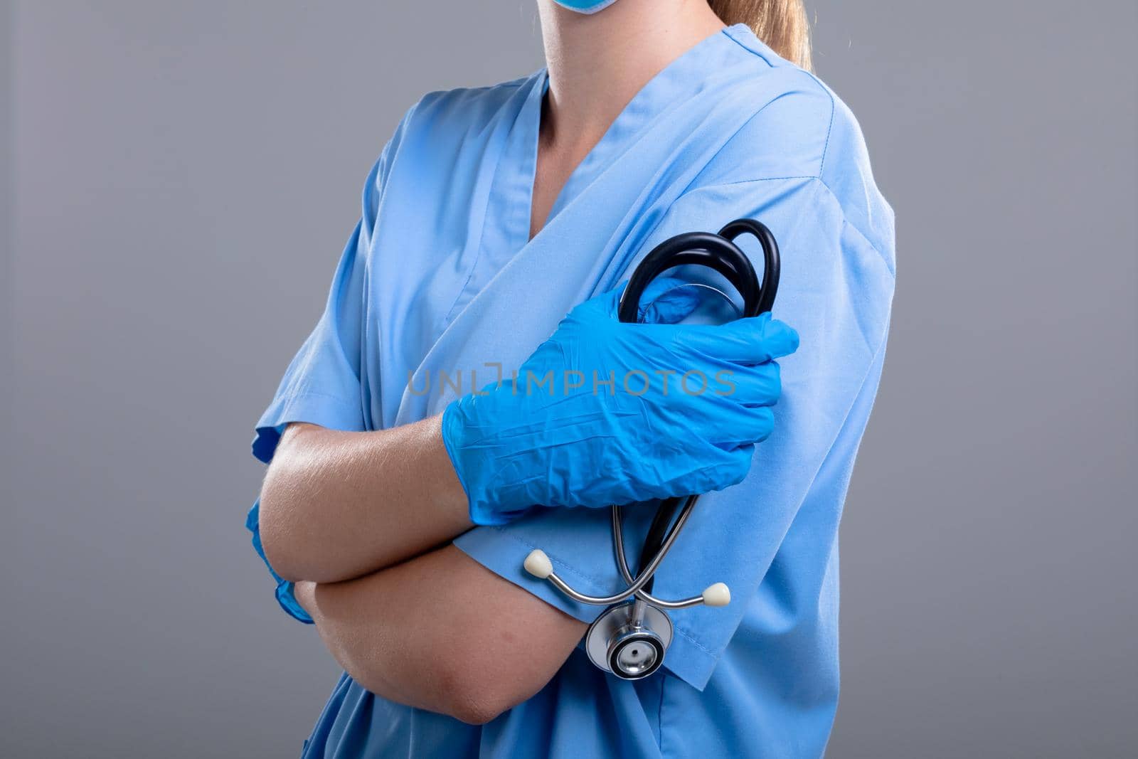 Midsection of caucasian female doctor holding stethoscope, isolated on grey background. medical and healthcare services concept.