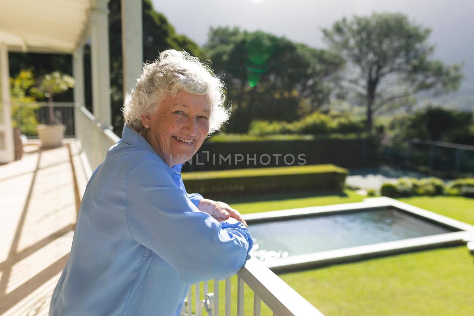 Portrait of senior caucasian woman standing on balcony and smiling. retreat, retirement and happy senior lifestyle concept.