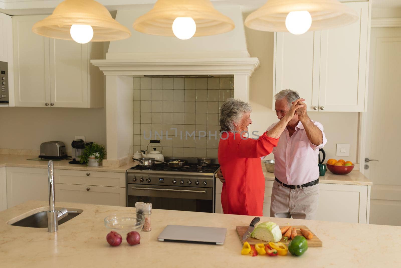 Senior caucasian couple dancing together and smiling in kitchen by Wavebreakmedia