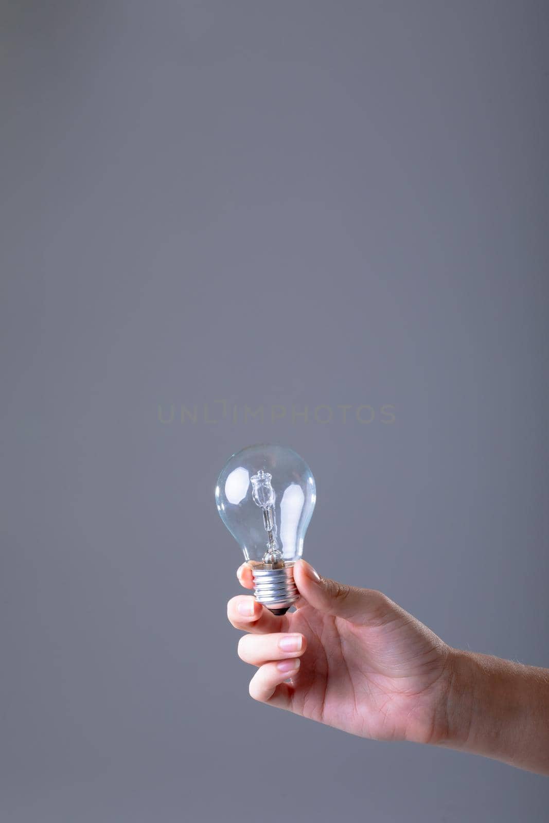 Close up of caucasian businesswoman holding light bulb, isolated on grey background by Wavebreakmedia