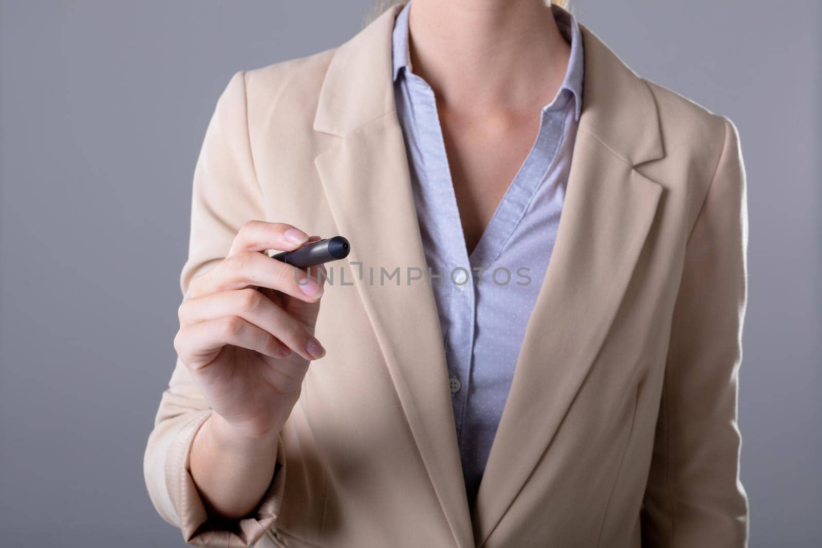 Midsection of caucasian businesswoman holding pen, isolated on grey background. business, technology, communication and growth concept.