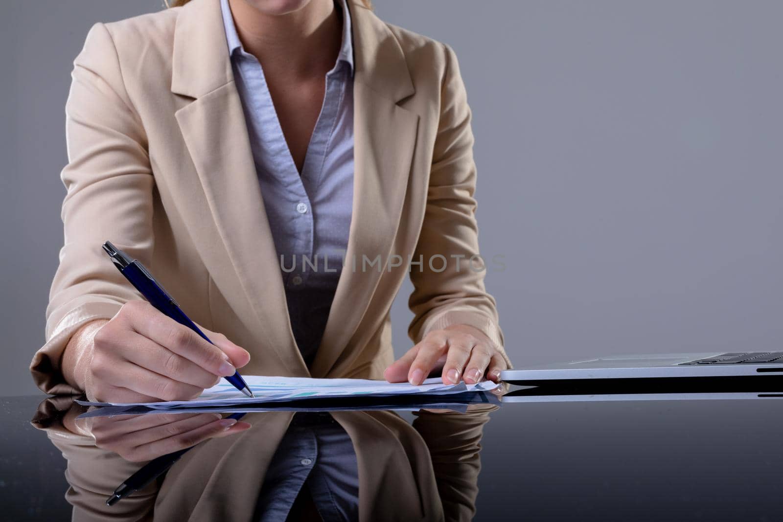 Midsection of caucasian businesswoman using laptop and taking notes, isolated on grey background. business, technology, communication and growth concept.