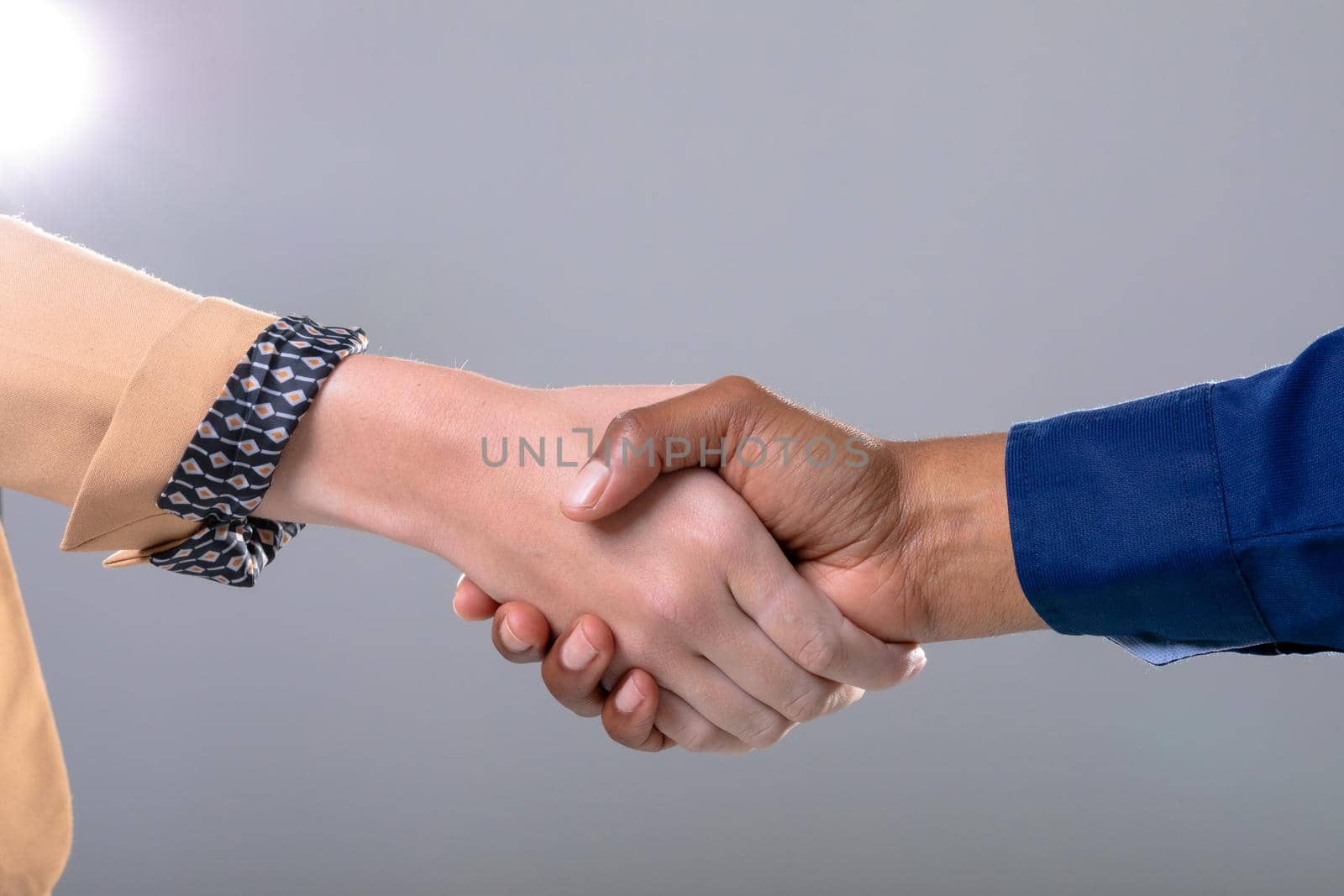 Midsection of caucasian and african american business people shaking hands on grey background by Wavebreakmedia