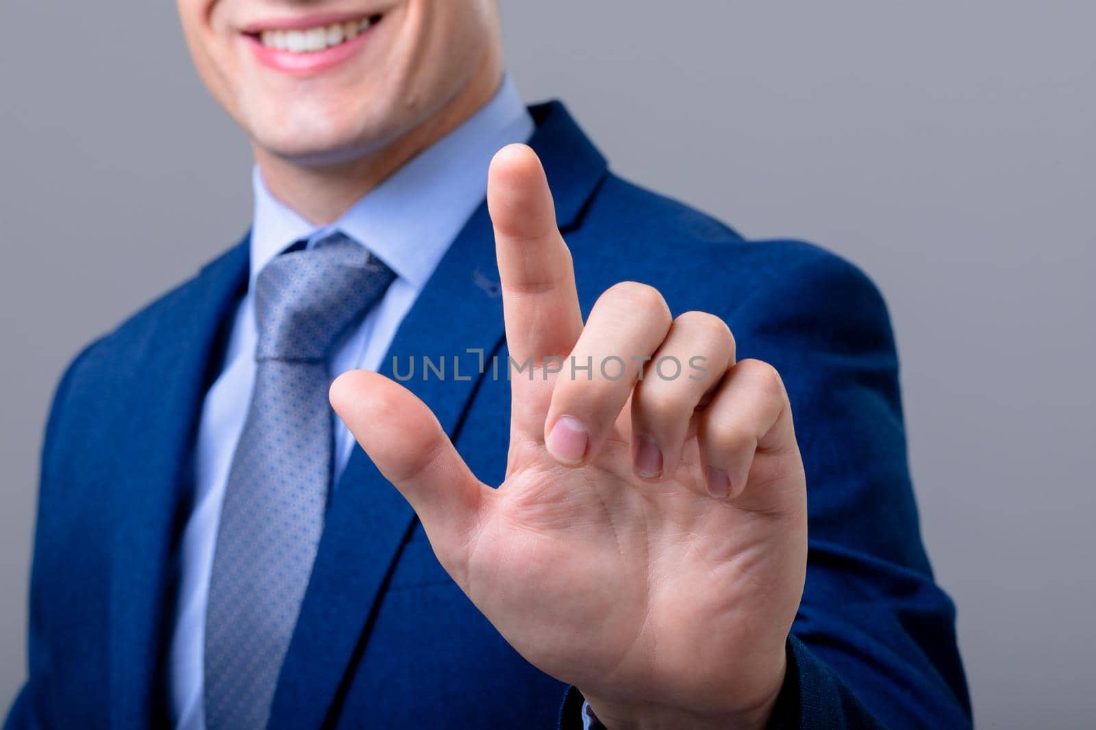 Midsection of caucasian businessman touching virtual interface, isolated on grey background. business technology, communication and growth concept.