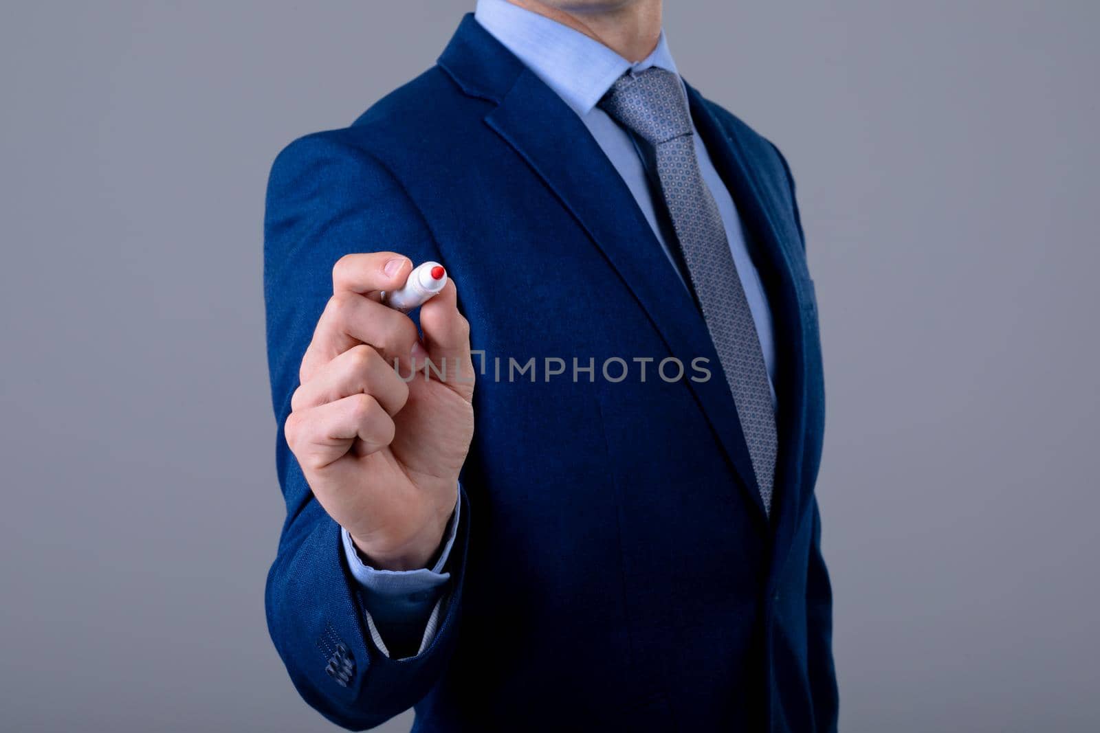 Midsection of caucasian businessman holding pen, isolated on grey background by Wavebreakmedia