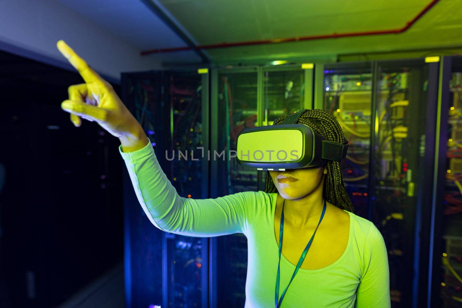 African american female computer technician wearing vr headset and working in server room. digital information storage and communication network technology.