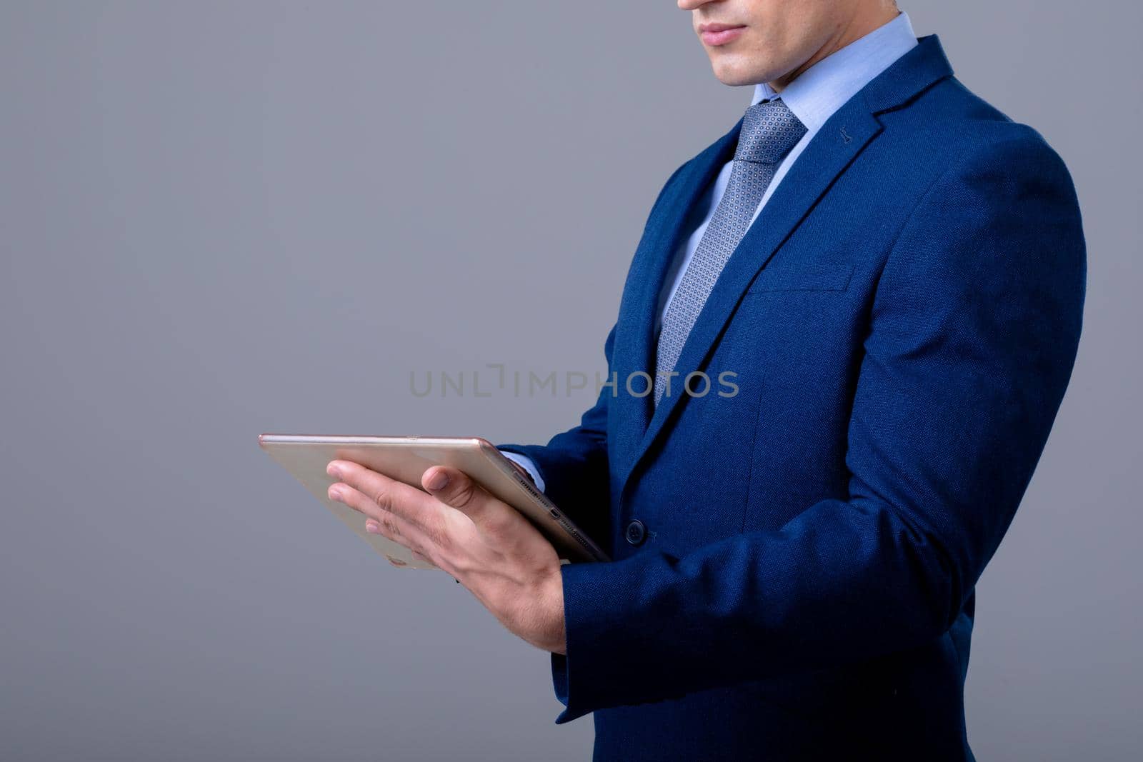 Caucasian businessman using digital tablet, isolated on grey background by Wavebreakmedia