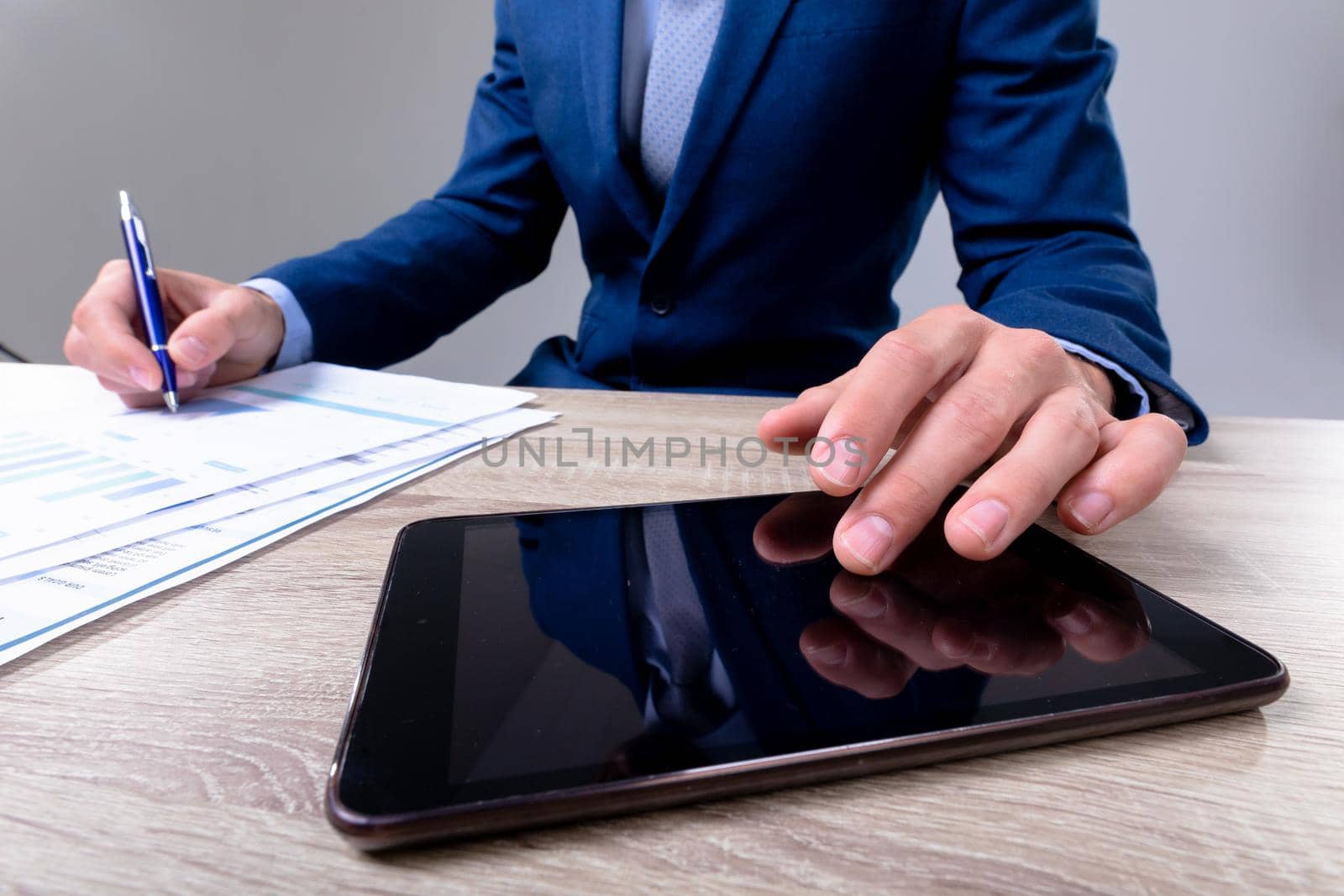 Midsection of caucasian businessman using tablet and taking notes, isolated on grey background. business technology, communication and growth concept.