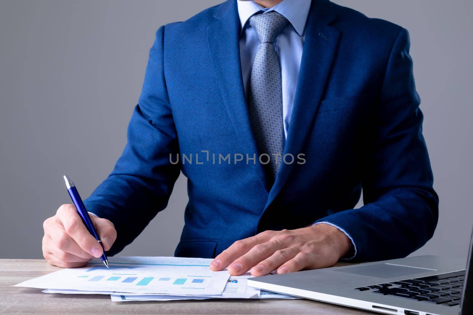 Midsection of caucasian businessman using laptop and taking notes, isolated on grey background by Wavebreakmedia