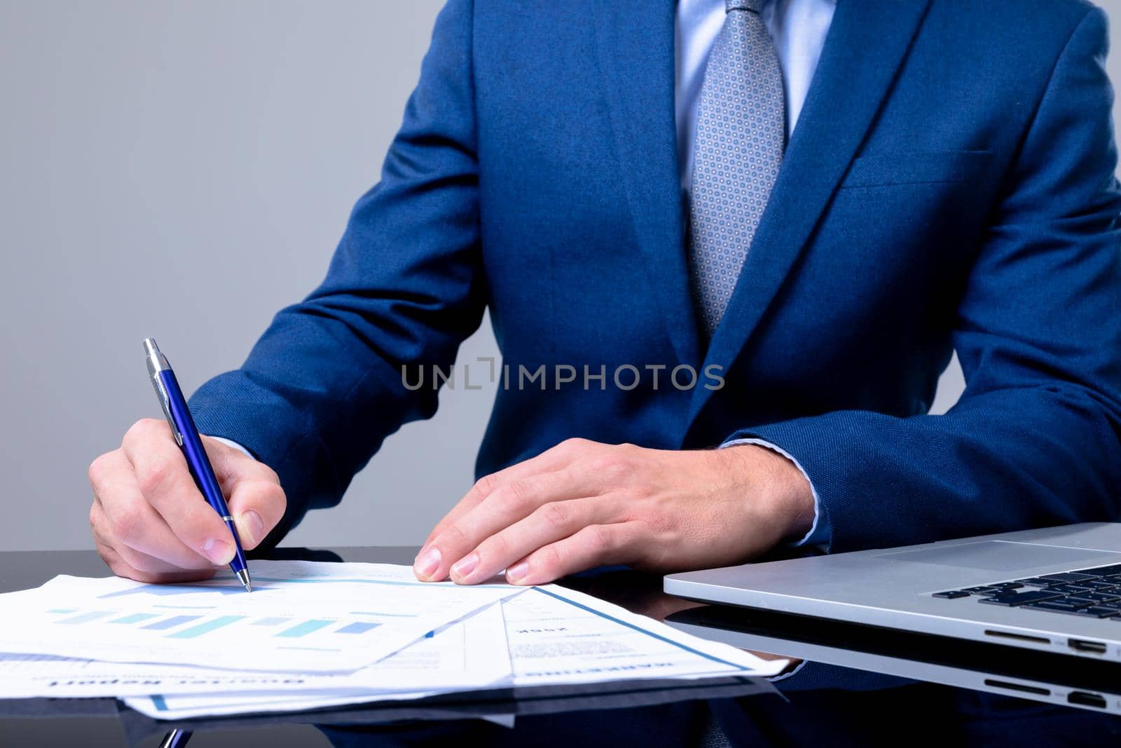 Midsection of caucasian businessman using laptop and taking notes, isolated on grey background by Wavebreakmedia