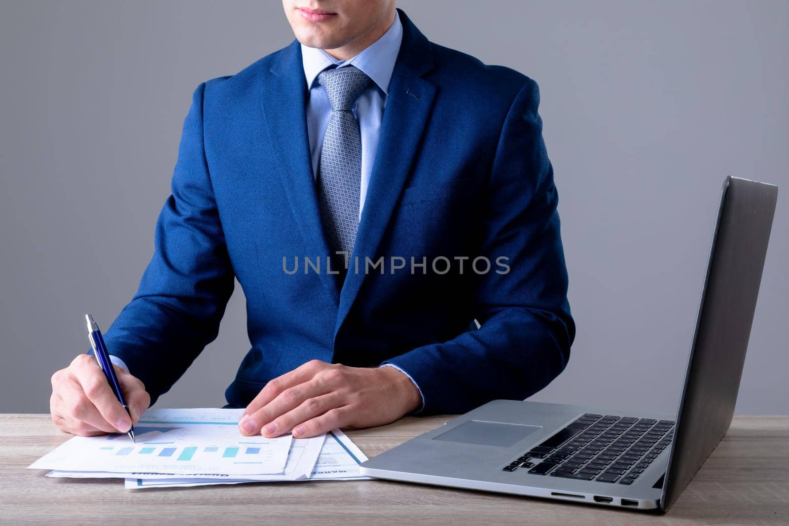 Midsection of caucasian businessman using laptop and taking notes, isolated on grey background. business technology, communication and growth concept.