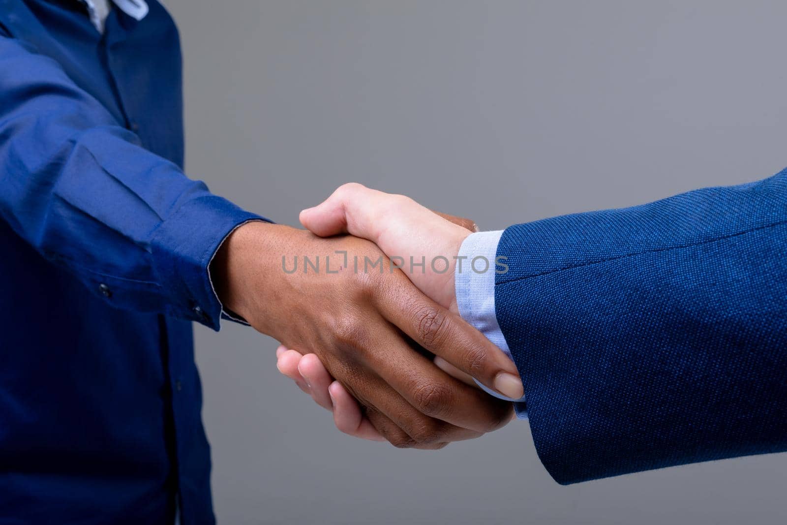 Caucasian and african american business people shaking hands, isolated on grey background. business technology, communication and growth concept.