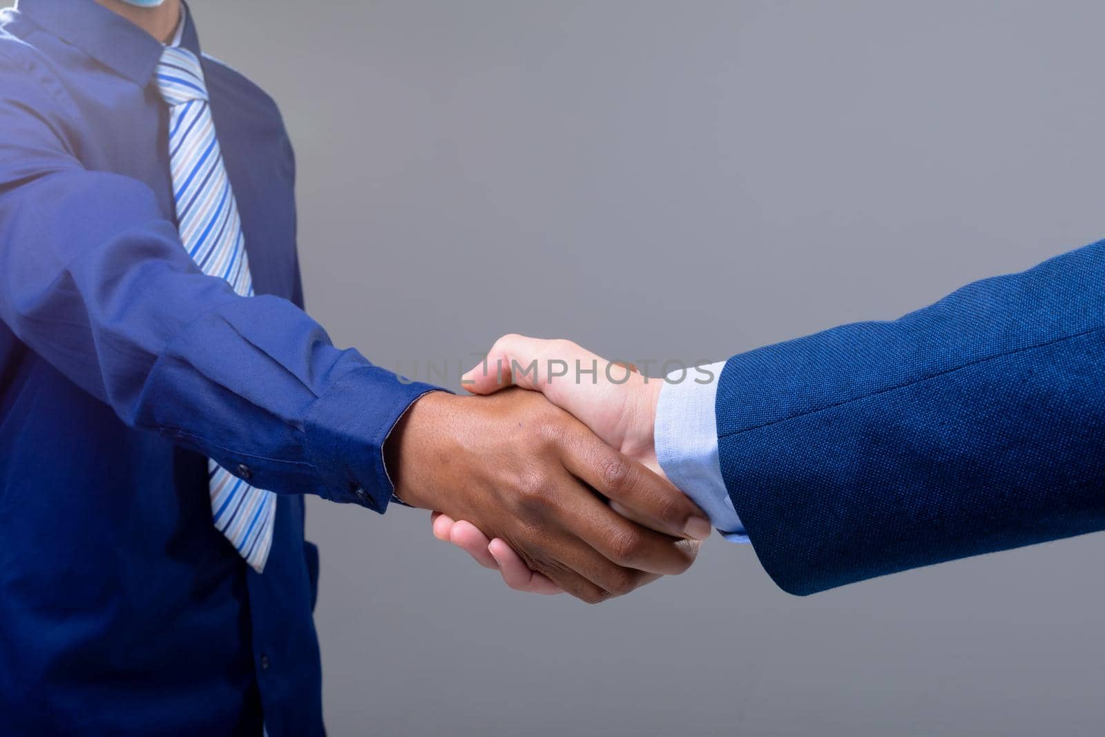 Caucasian and african american business people shaking hands, isolated on grey background. business technology, communication and growth concept.