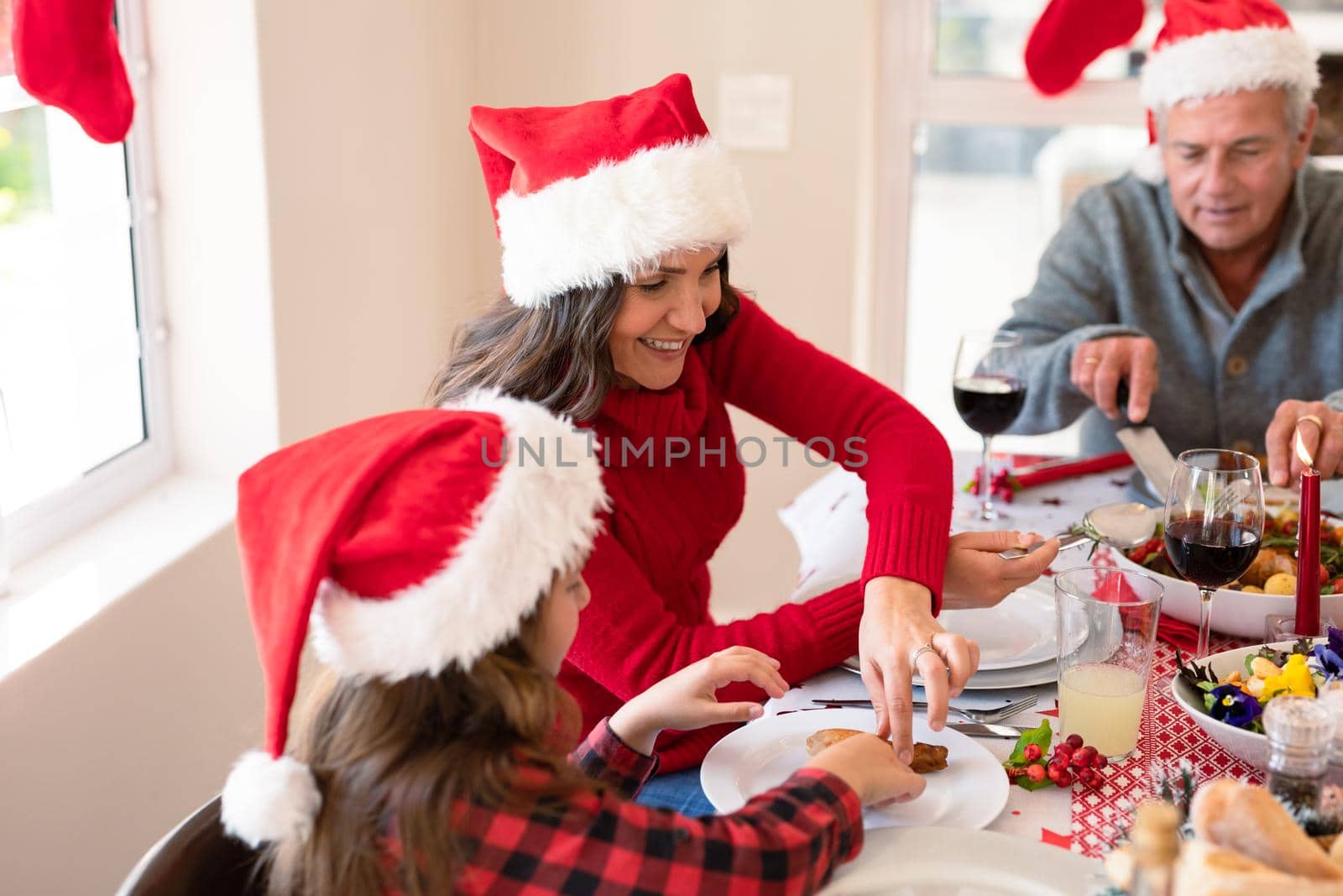 Caucasian multi generation family wearing santa hats having christmas meal. family christmas time and festivity together at home.