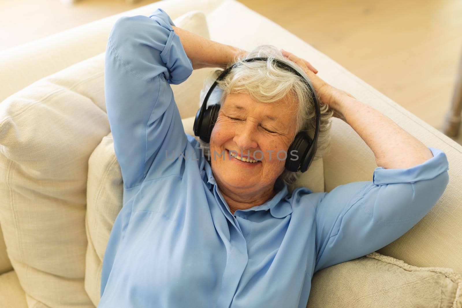 Senior caucasian woman sitting on sofa wearing headphones with eyes closed by Wavebreakmedia