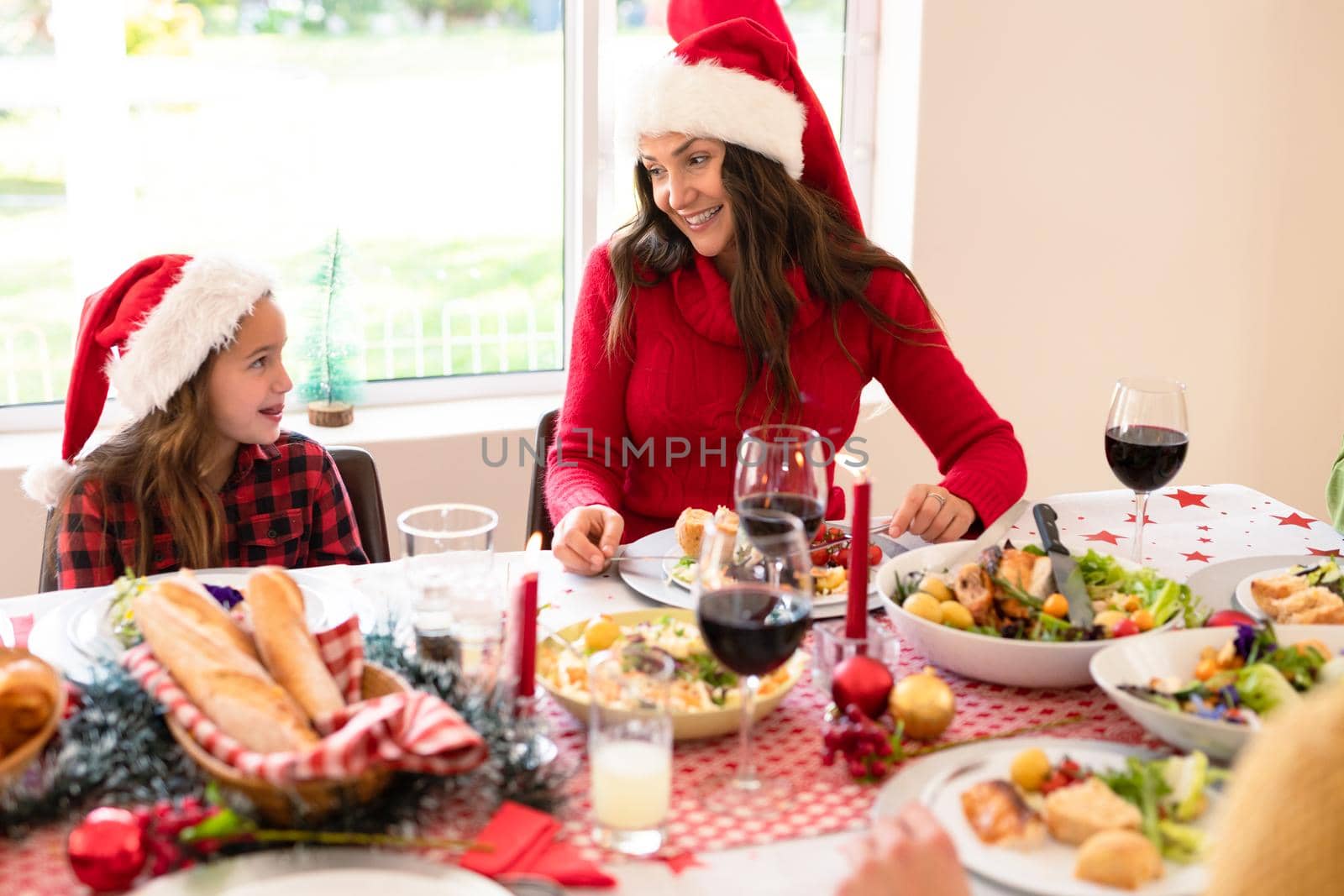 Happymother and daughter wearing santa hats sitting at christmas table. family christmas time and festivity together at home.