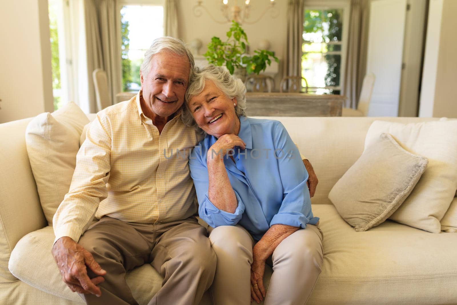 Portrait of senior caucasian couple sitting on sofa embracing and smiling by Wavebreakmedia