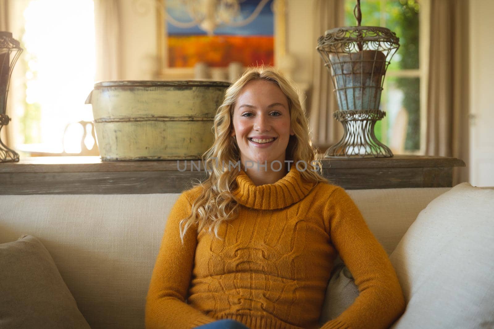 Portrait of happy caucasian woman sitting on couch in luxury living room, smiling. spending free time at home.