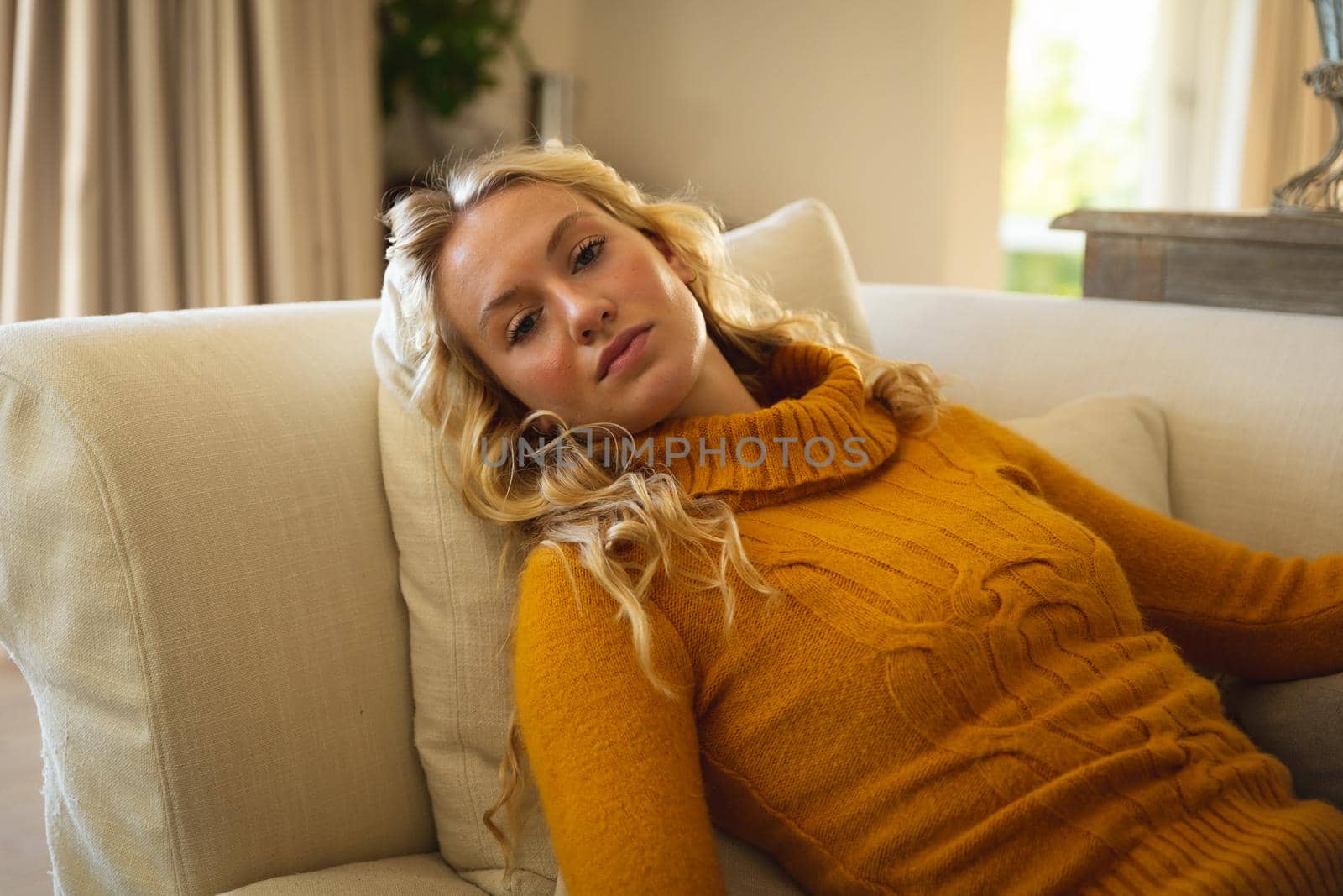 Portrait of thoughtful caucasian woman lying back on couch relaxing n luxury living room. spending free time at home.