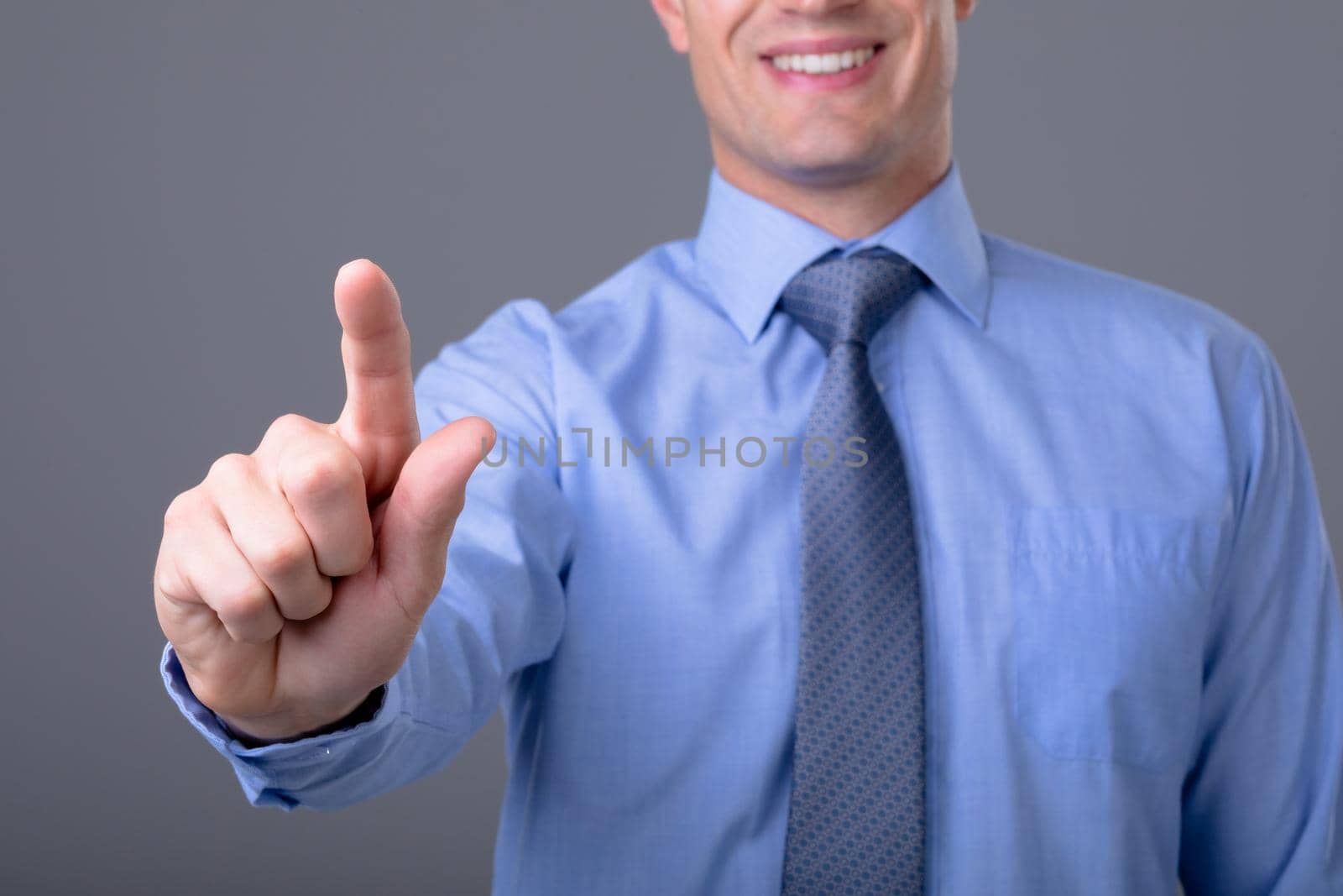 Midsection of caucasian businessman touching virtual interface, isolated on grey background. business technology, communication and growth concept.