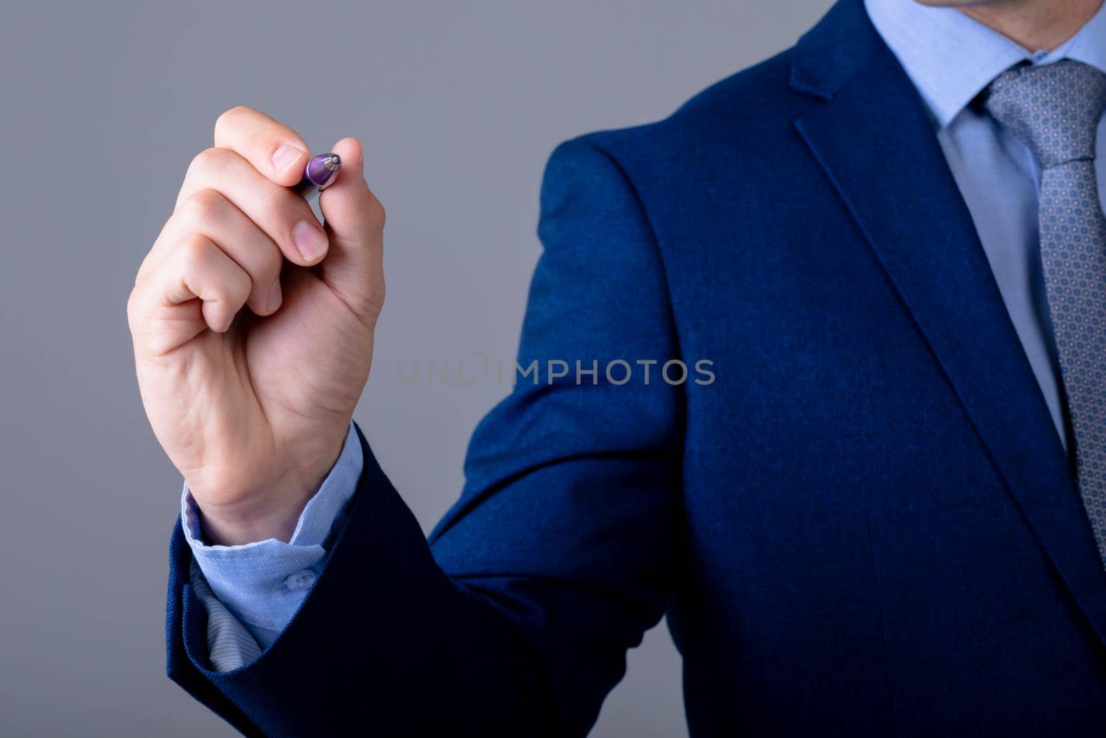 Midsection of caucasian businessman holding pen, isolated on grey background by Wavebreakmedia