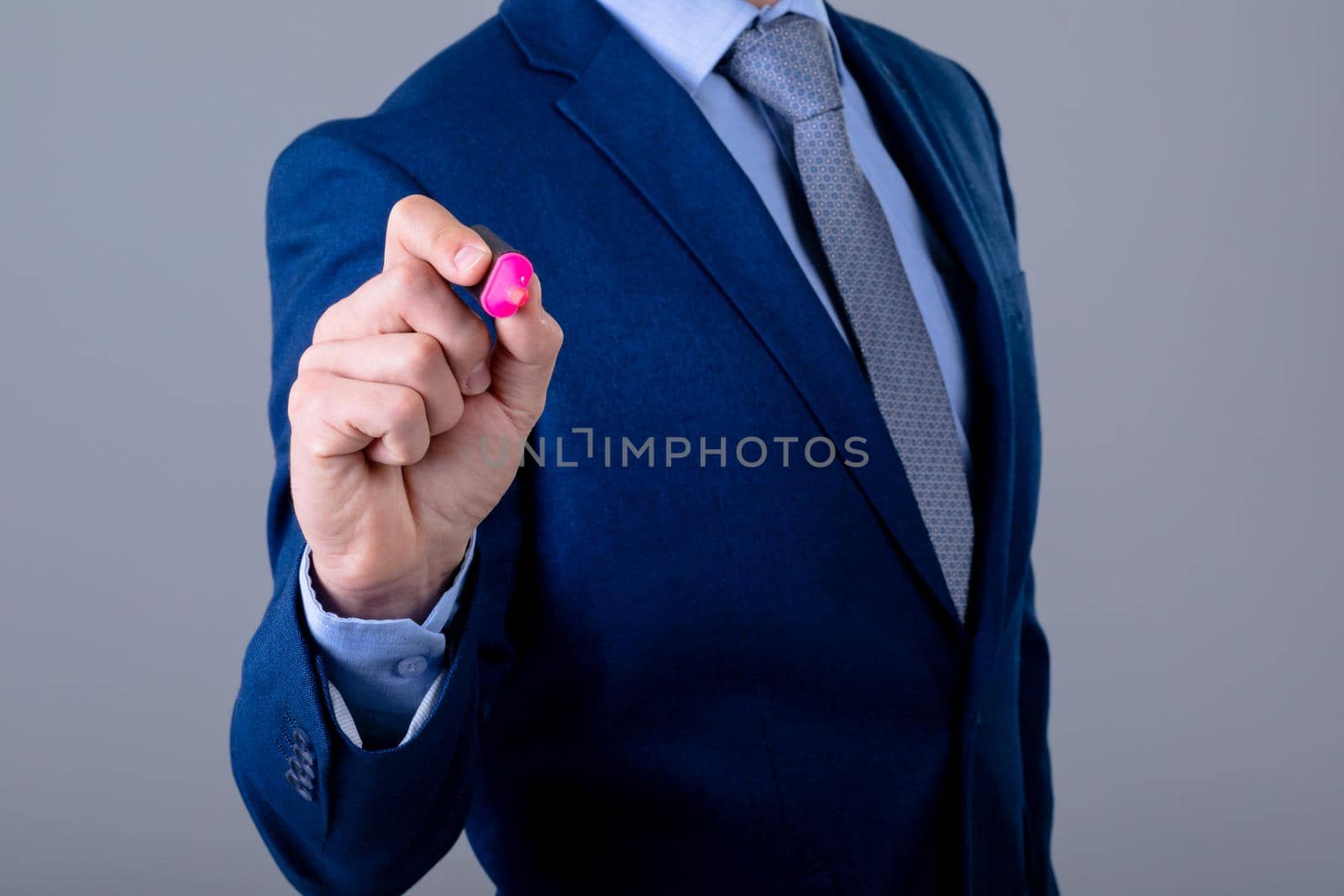 Midsection of caucasian businessman holding marker, isolated on grey background. business technology, communication and growth concept.