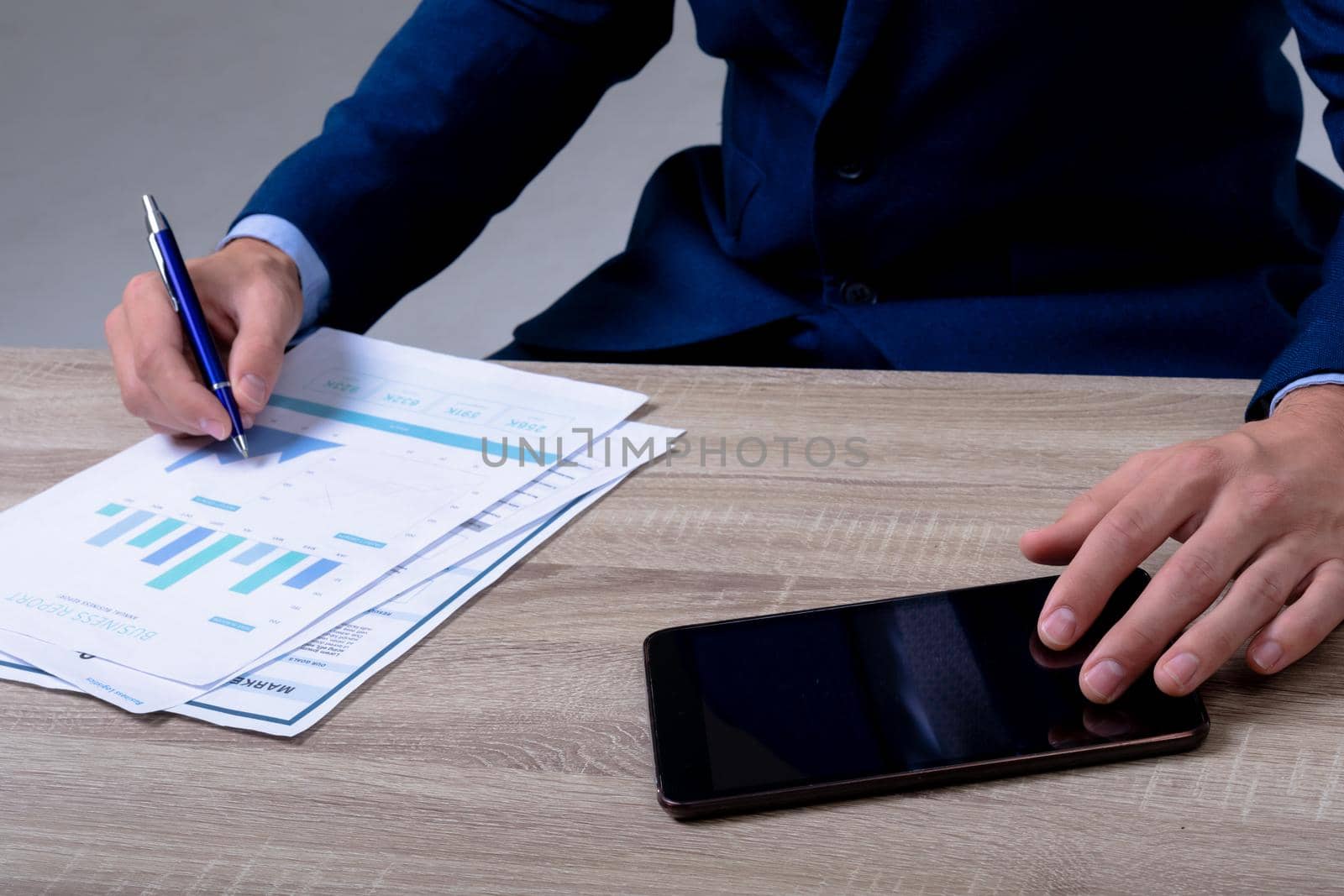Midsection of caucasian businessman using smartphone and taking notes, isolated on grey background by Wavebreakmedia