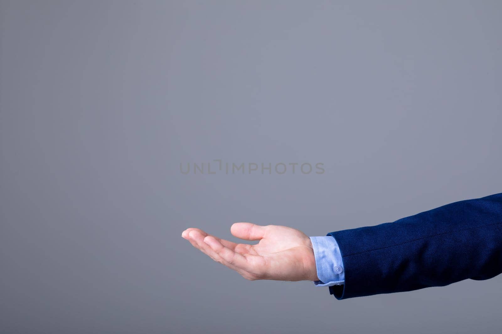 Midsection of caucasian businessman reaching his hand, isolated on grey background by Wavebreakmedia