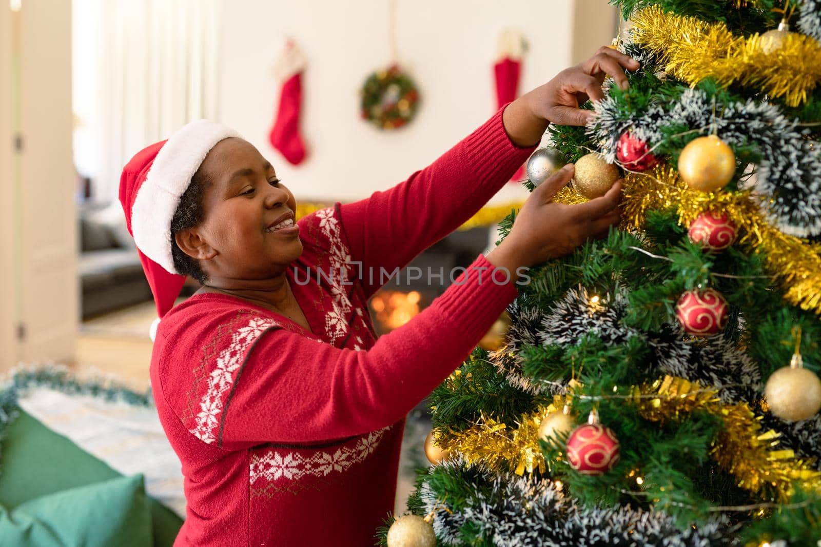 Happy african american senior woman decorating christmas tree. retirement lifestyle and christmas festivities, celebrating at home.