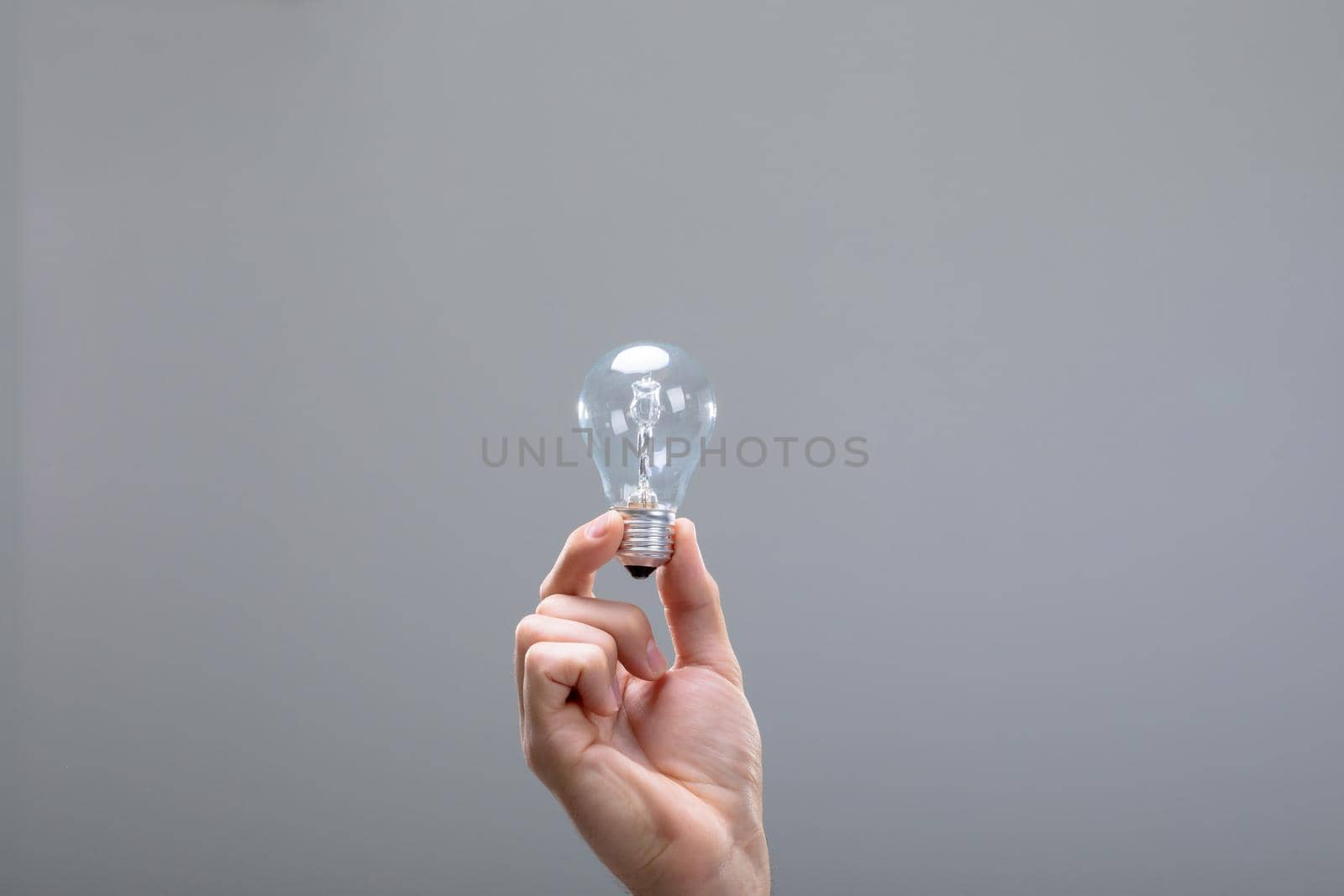 Close up of caucasian businessman holding light bulb, isolated on grey background. business technology, communication and growth concept.