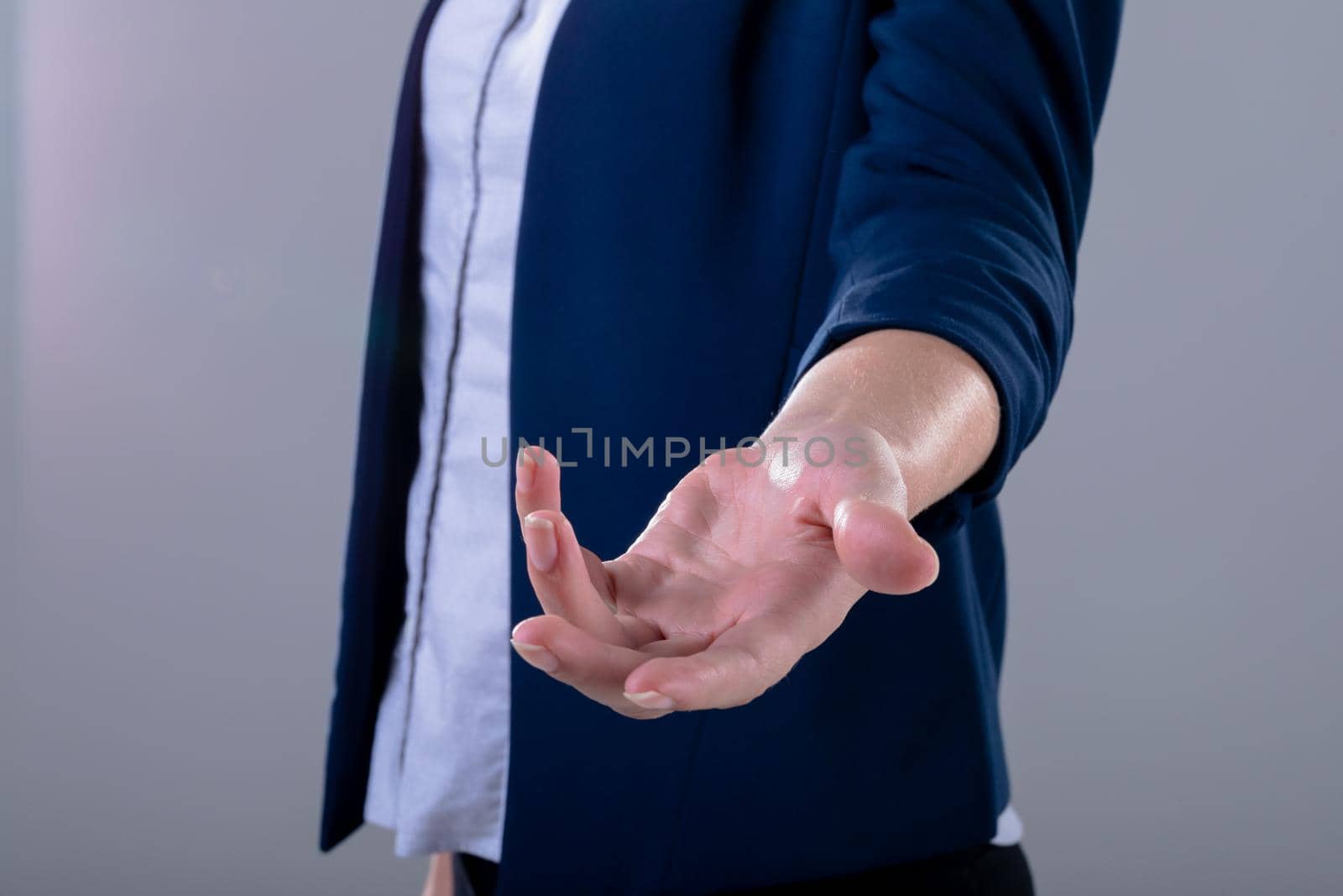 Midsection of caucasian businesswoman reaching with her hand, isolated on grey background. business technology, communication and growth concept digitally generated composite image.