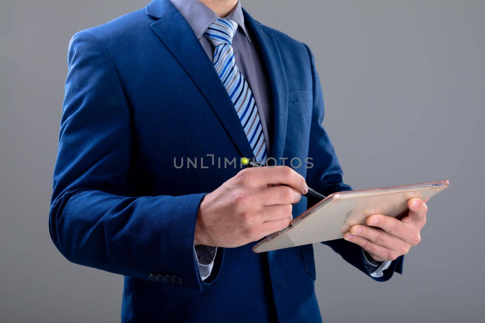 Midsection of caucasian businessman using tablet, isolated on grey background. business technology, communication and growth concept.