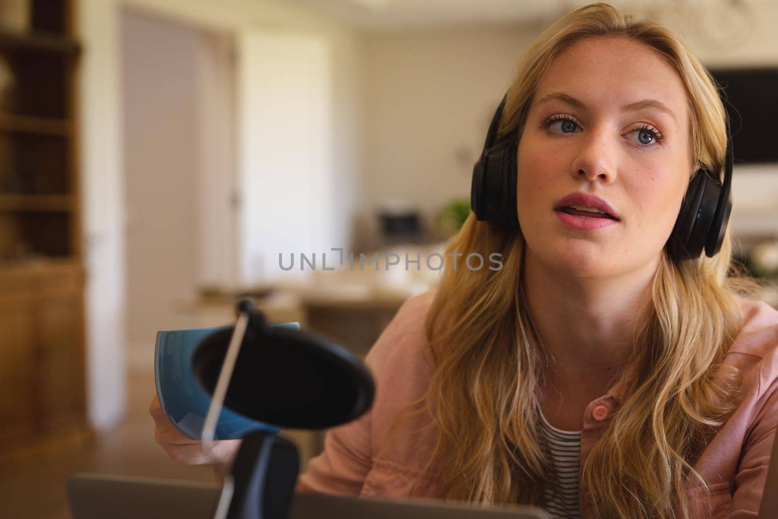 Caucasian woman wearing headphones and using microphone, talking during podcast. technology and communication, podcasting online from home.