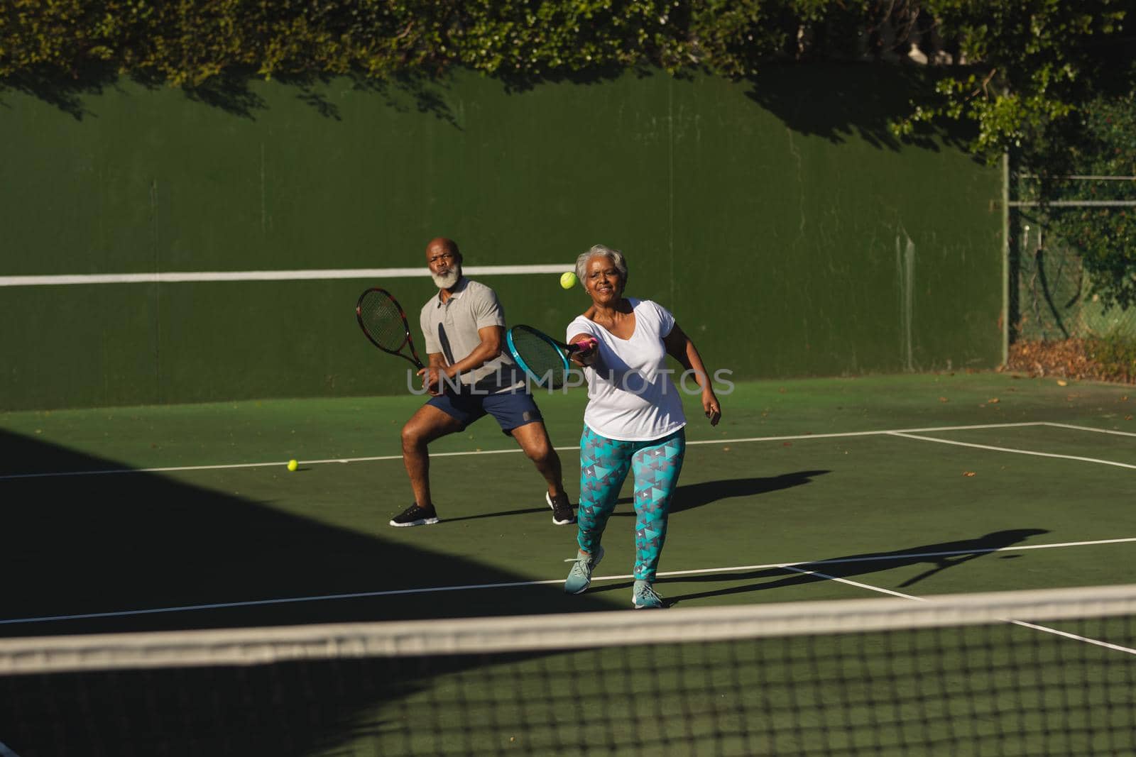 Senior african american couple playing tennis on tennis court by Wavebreakmedia