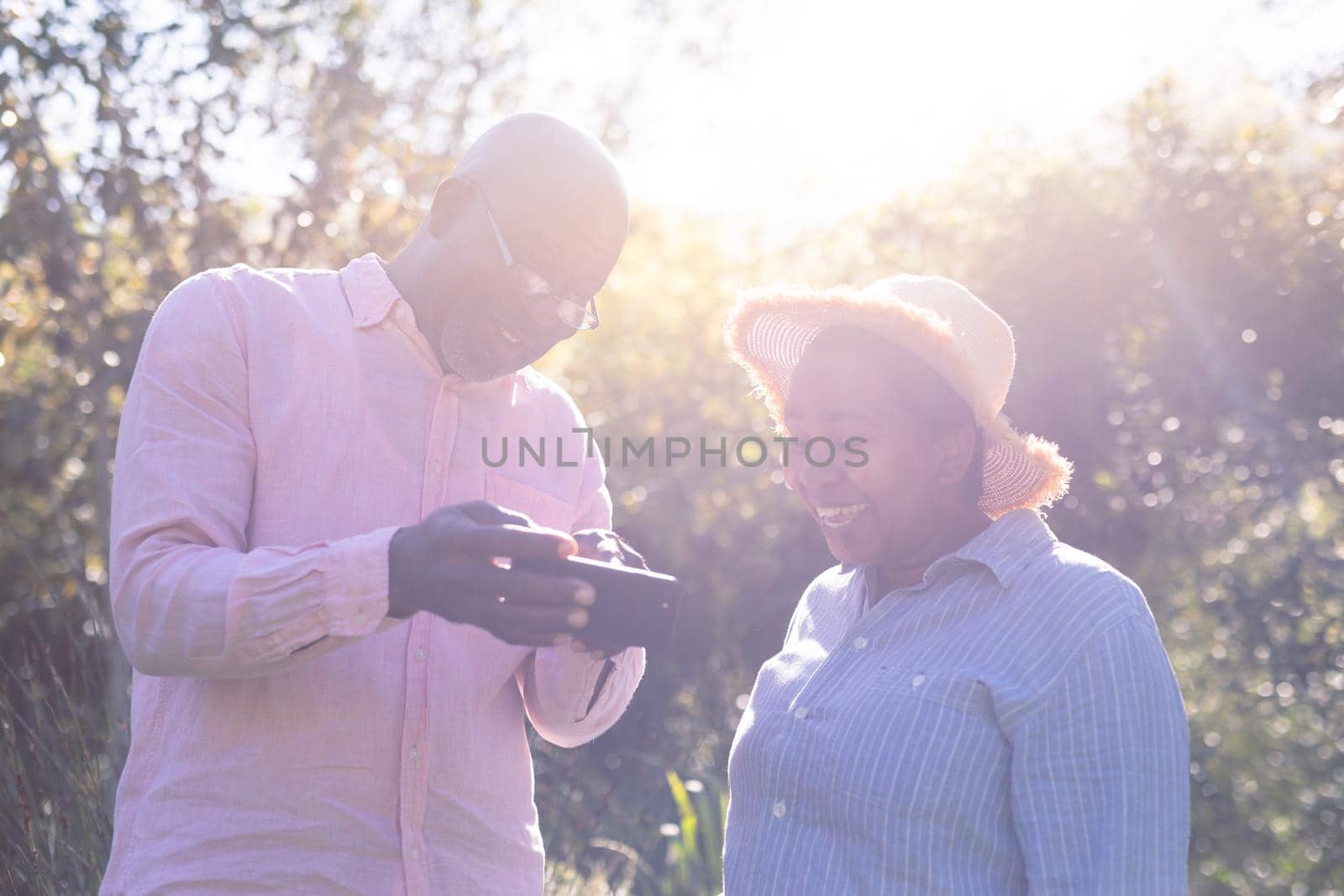 Happy african american senior couple taking selfie outdoors. retirement lifestyle, spending time at home and garden.