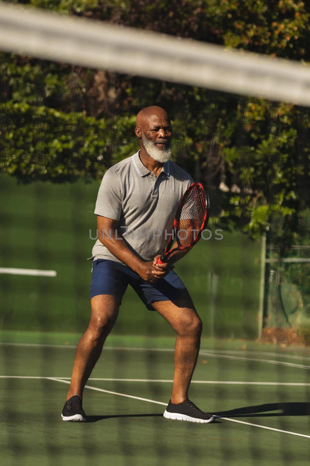 Senior african american man playing tennis on tennis court. retirement and active senior lifestyle concept.