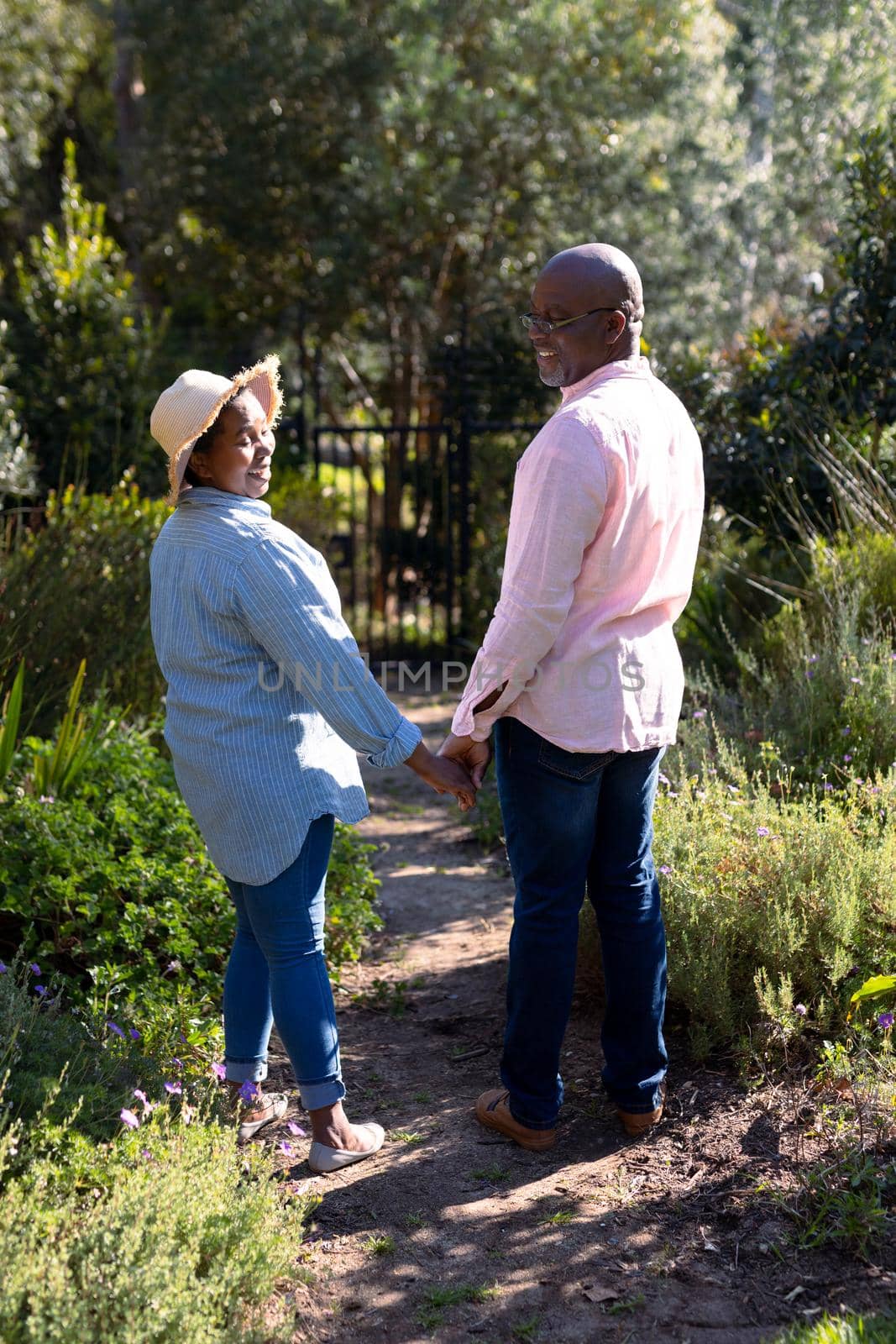 Happy african american senior couple holding hands outdoors. retirement lifestyle, spending time at home and garden.