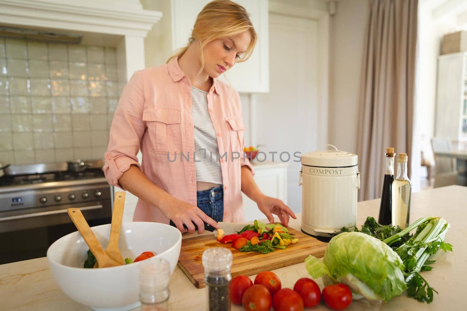 Caucasian woman standing in kitchen preparing food, chopping vegetables for salad. spending free time at home.