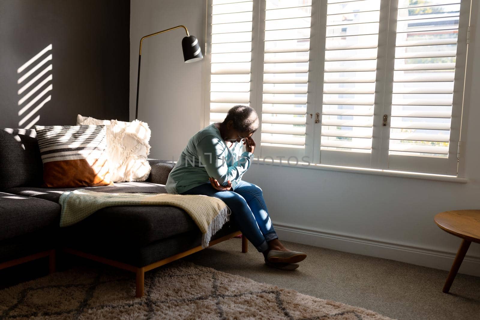 Tired african american senior woman sitting on bed at home. retirement lifestyle, spending time at home.