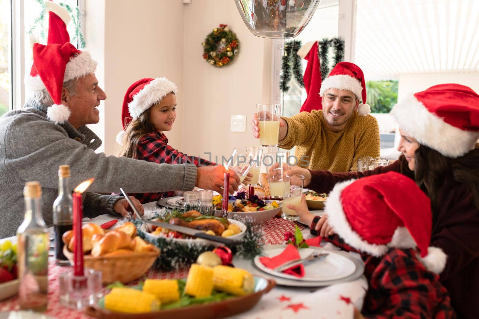 Caucasian multi generation family wearing santa hats having christmas meal. family christmas time and festivity together at home.