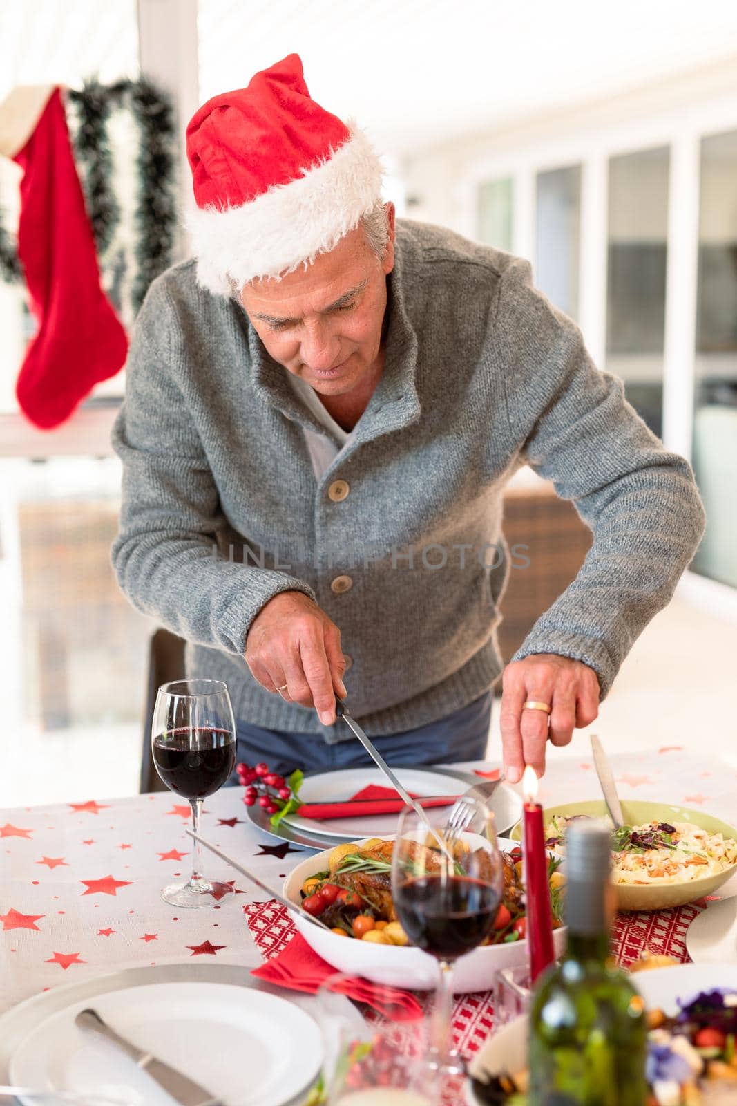 Happy caucasian senior man cutting food at christmas table by Wavebreakmedia