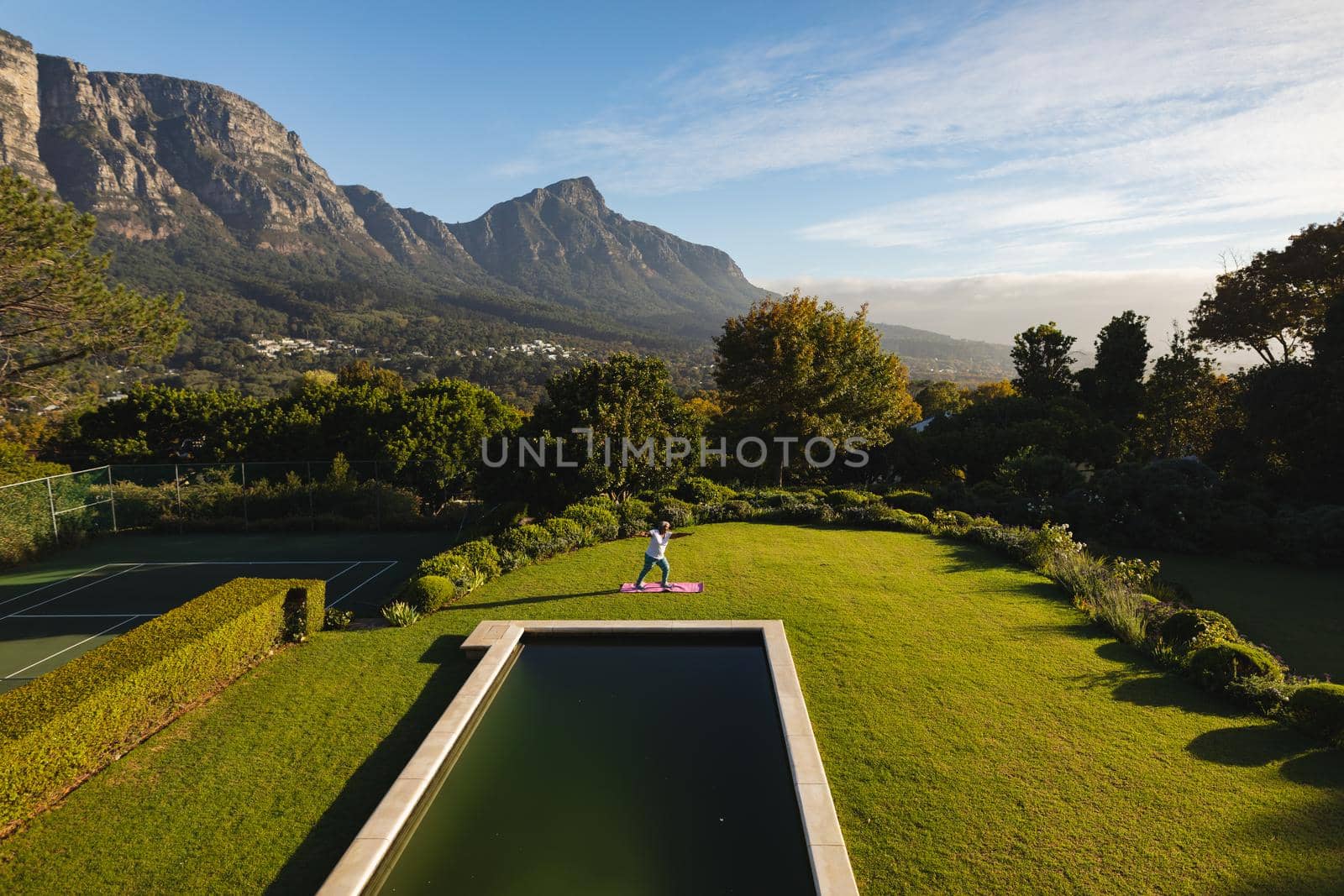 Senior african american woman practicing yoga on grass by outdoor pool in stunning countryside by Wavebreakmedia