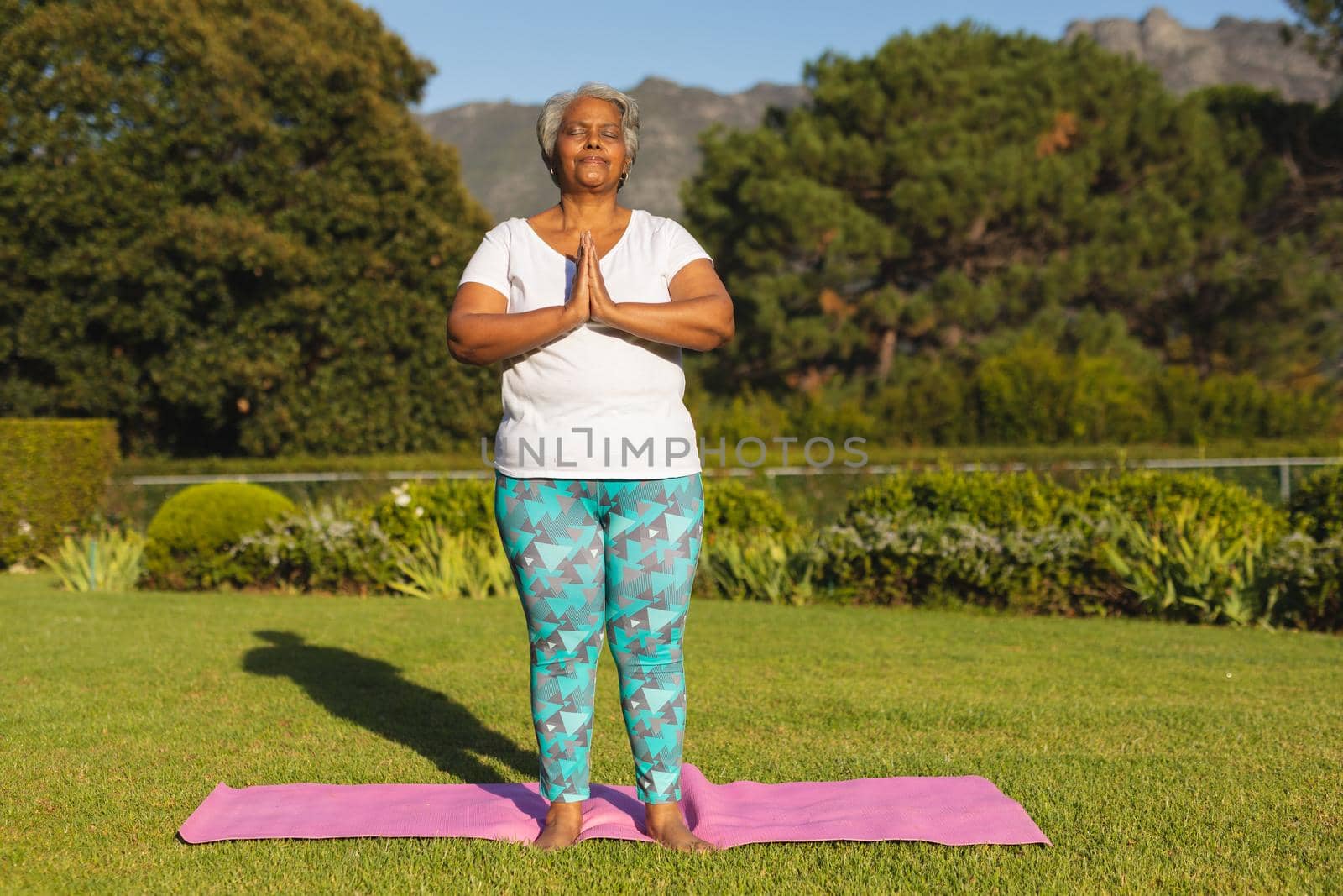 Senior african american woman with eyes closed practicing yoga in stunning countryside by Wavebreakmedia